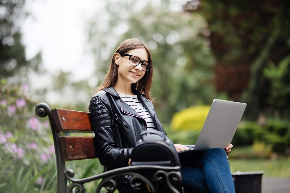 a woman sitting on a bench using a laptop