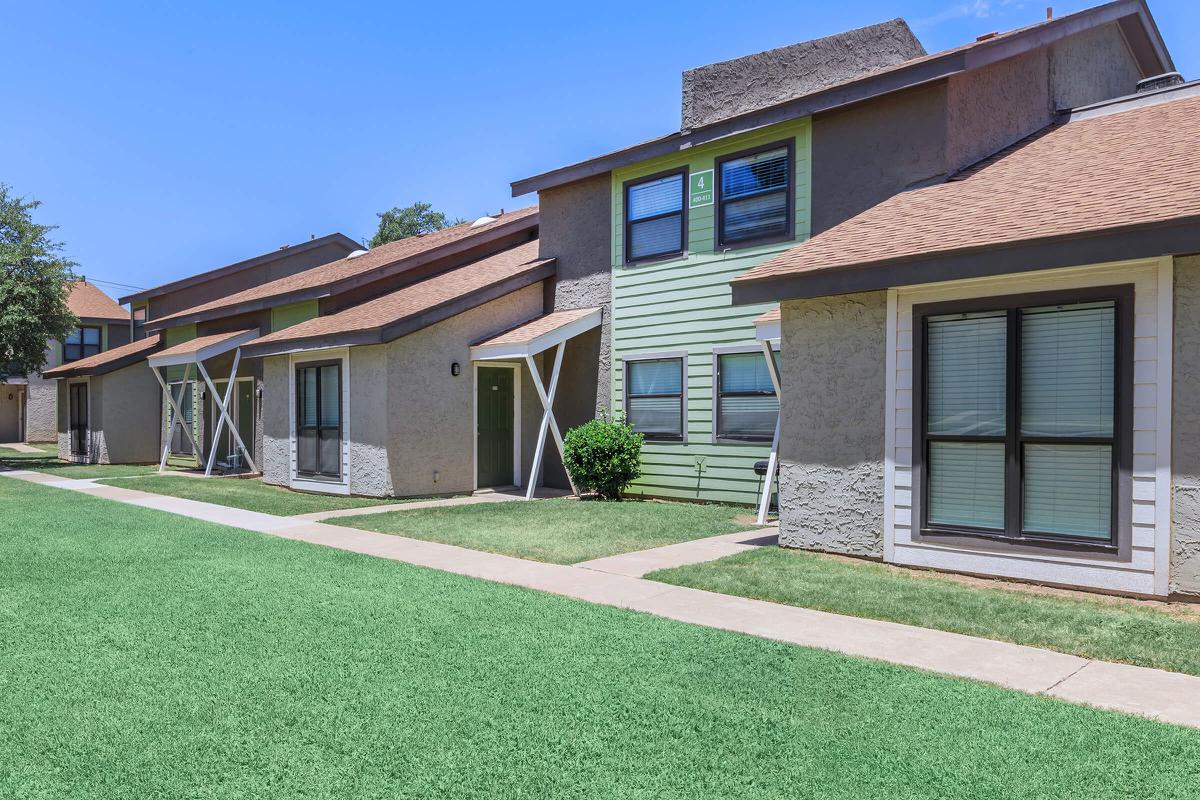 a house with a lawn in front of a brick building