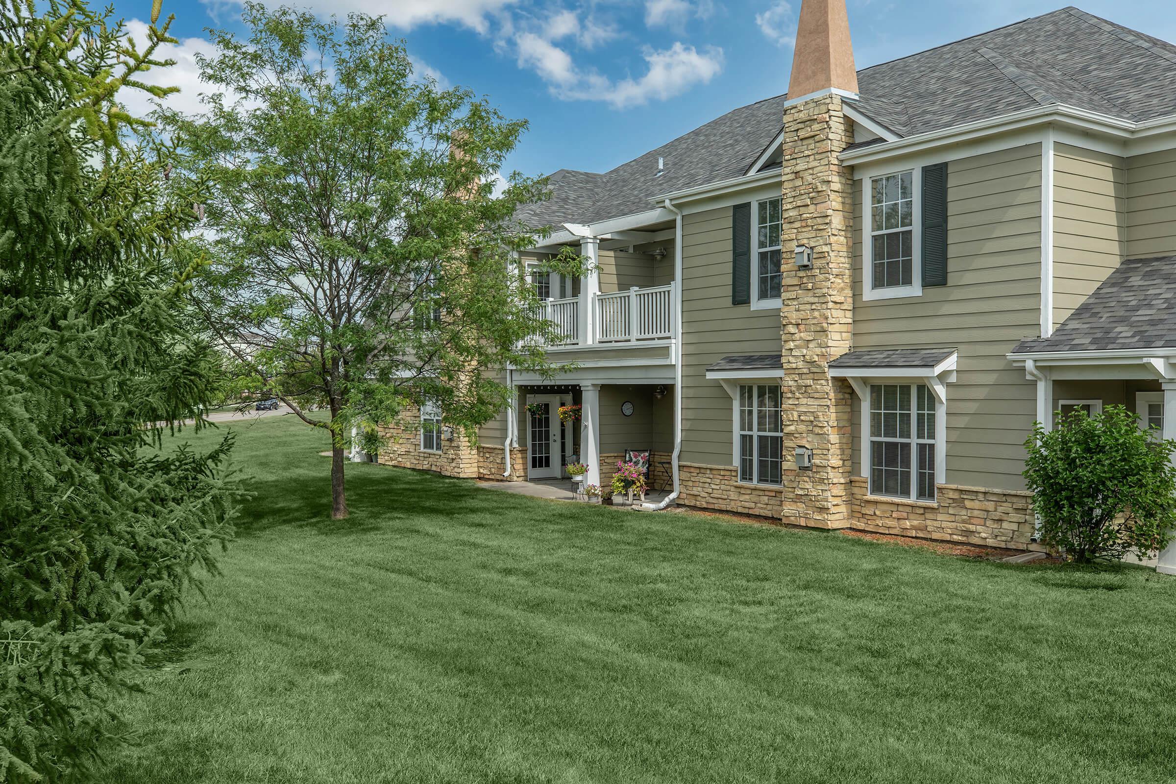 a large brick building with grass in front of a house