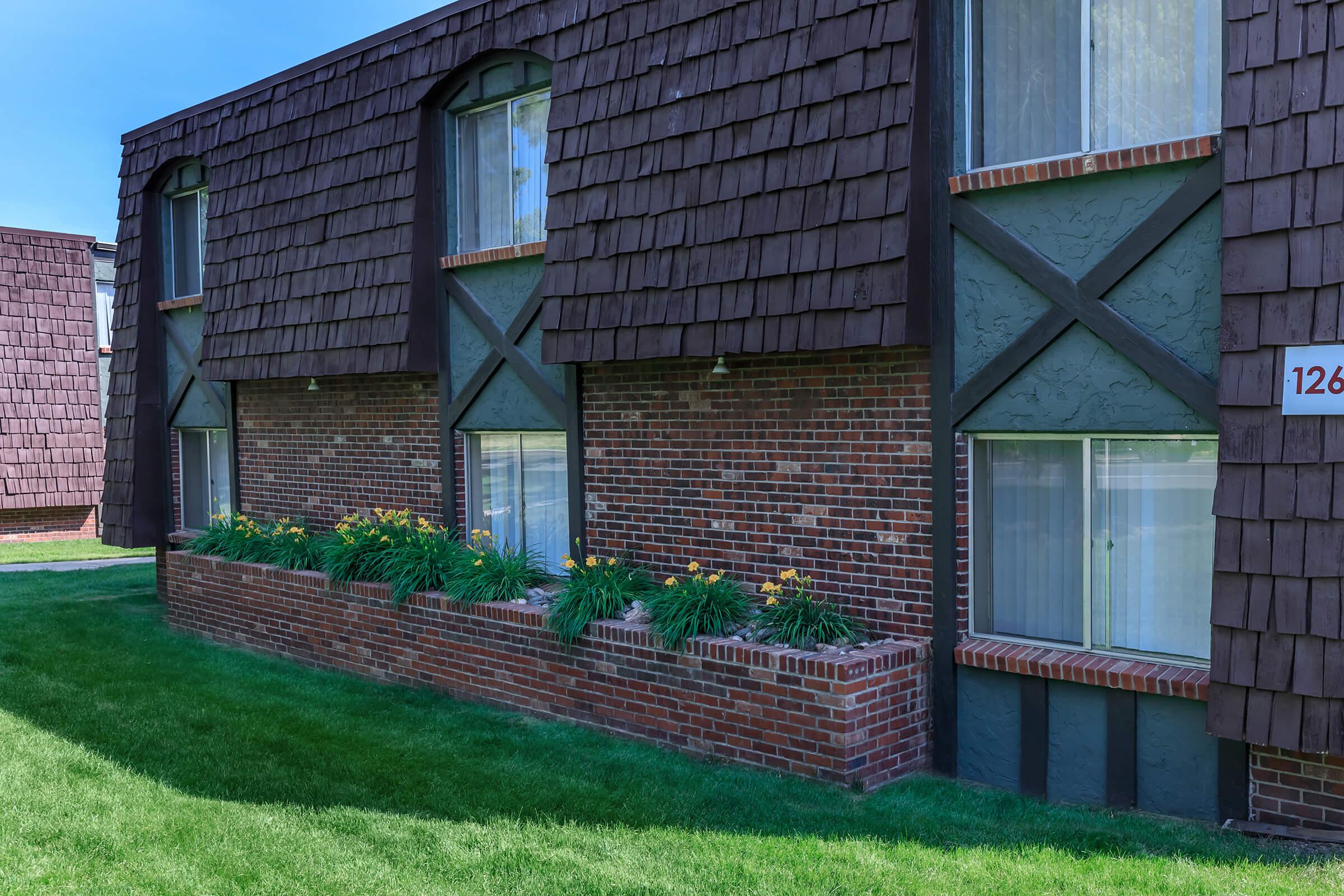 a large brick building with green grass