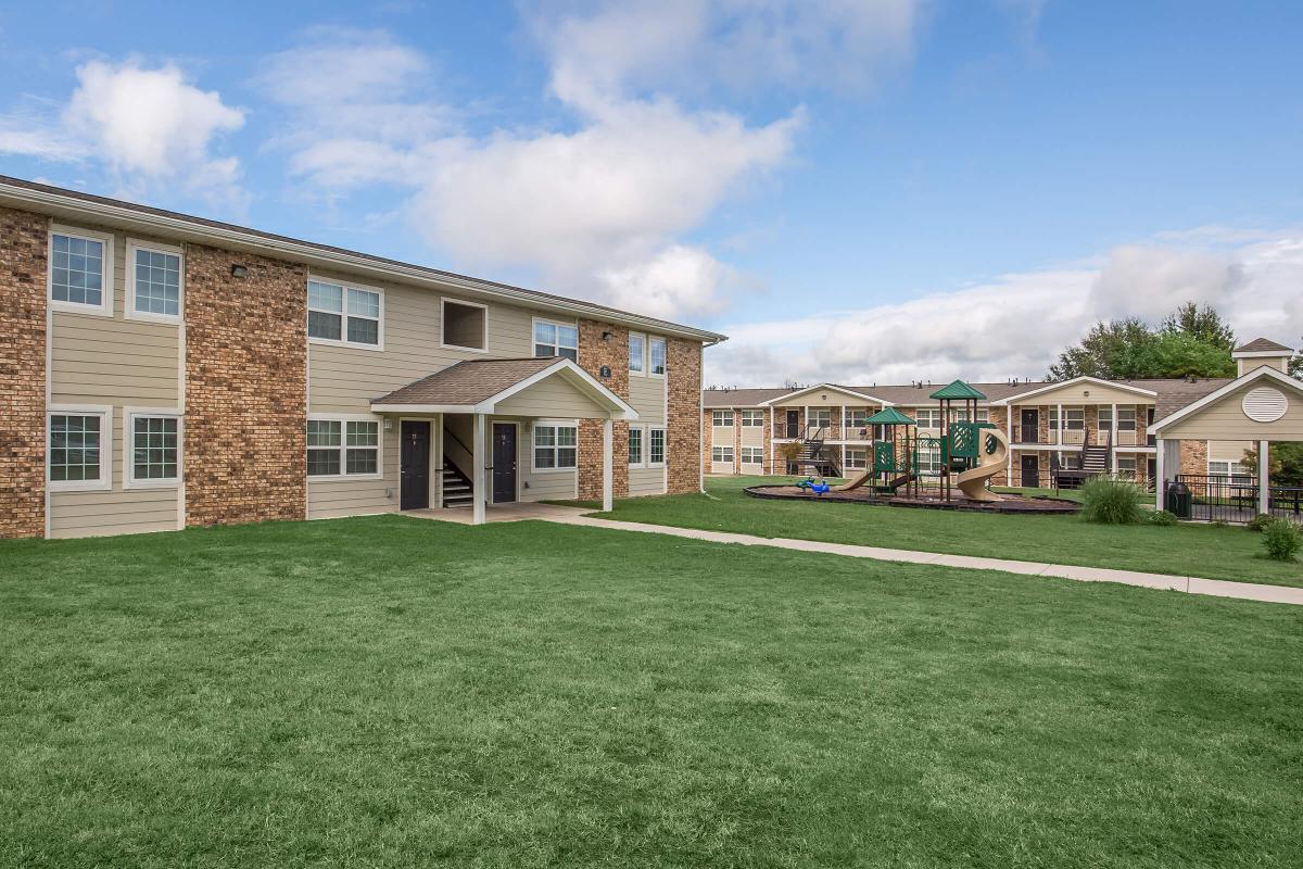 a large brick building with a grassy field