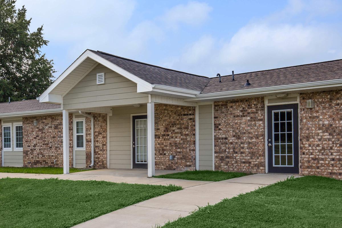 a large brick building with grass in front of a house