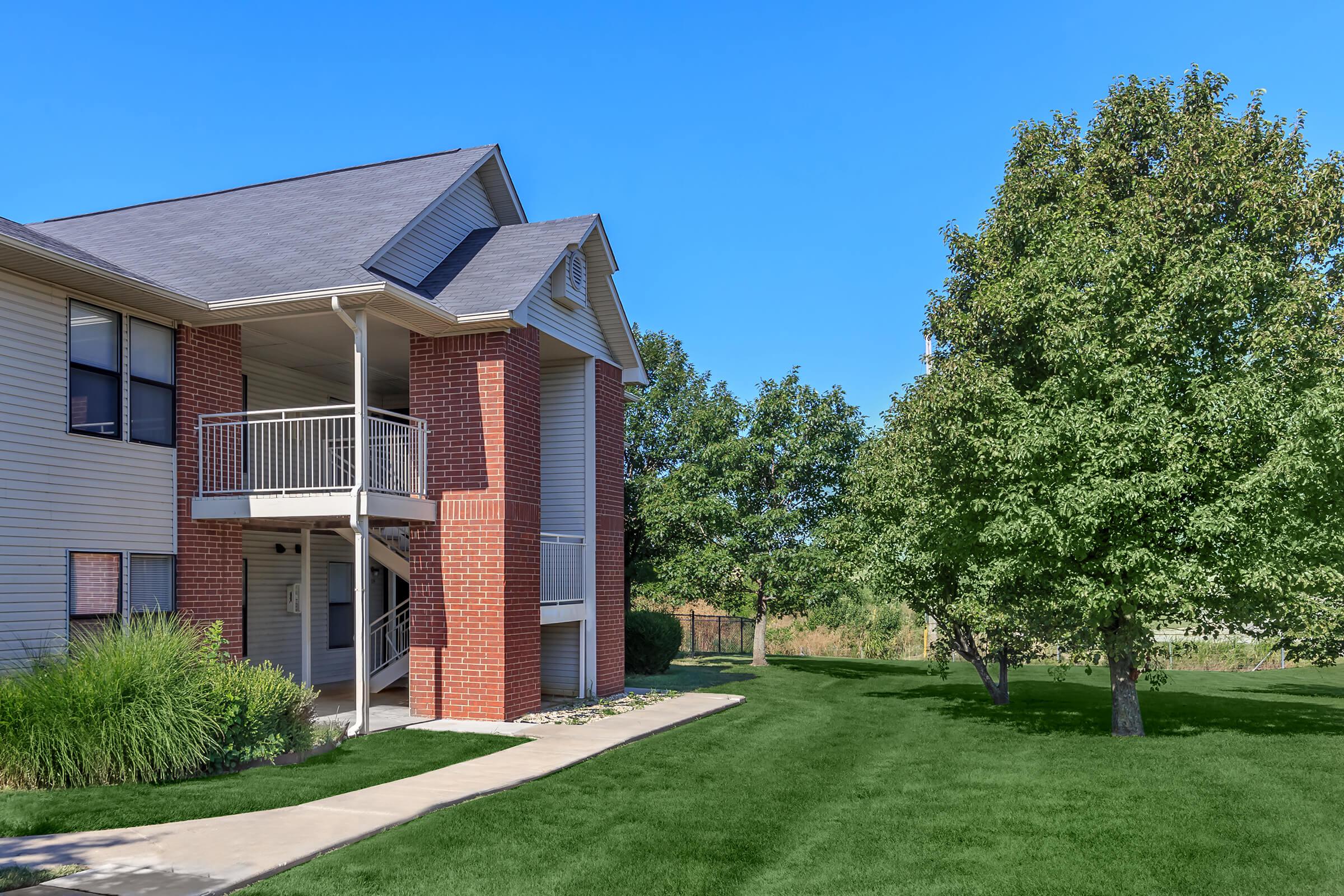 a large brick building with grass in front of a house