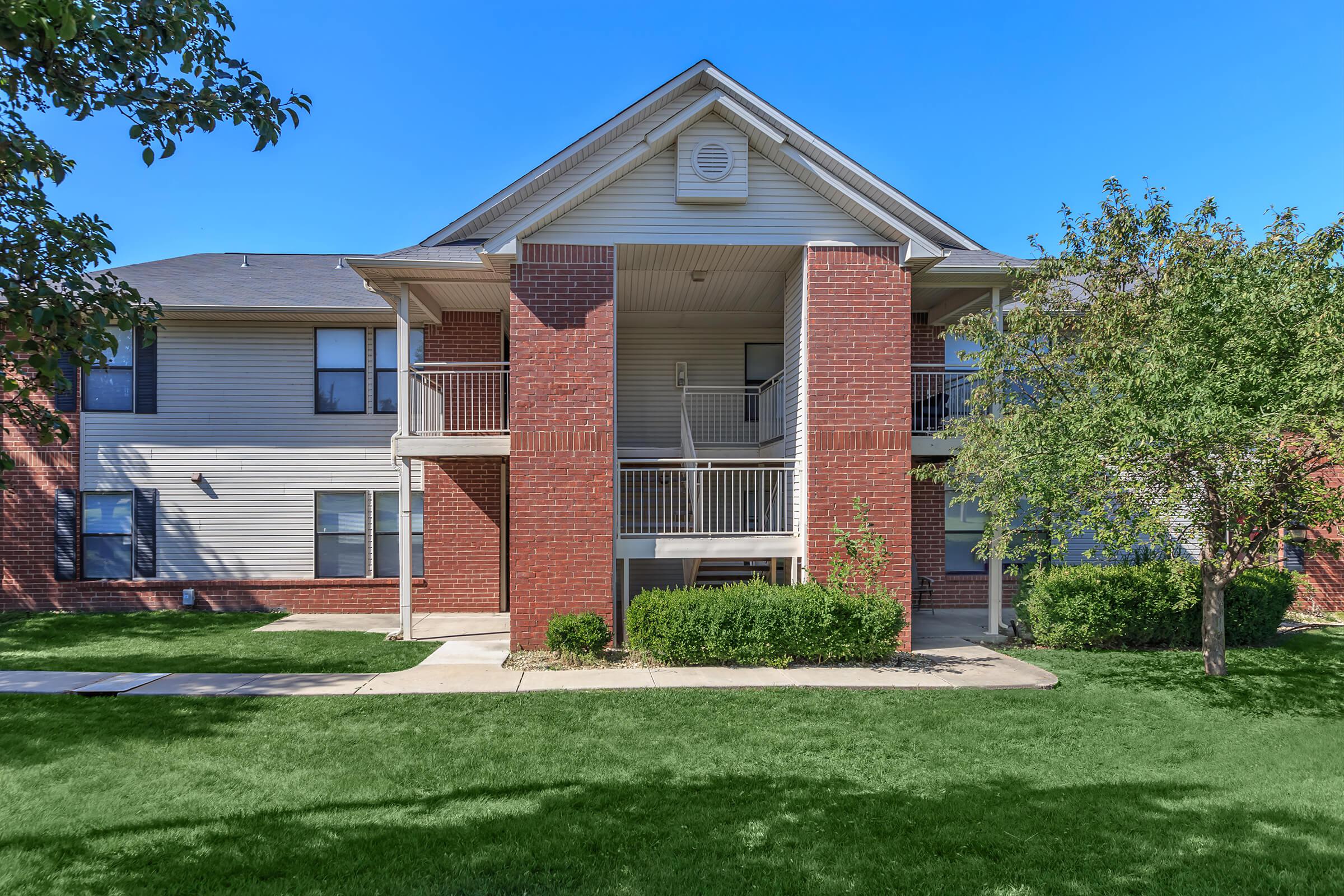 a house with a lawn in front of a brick building