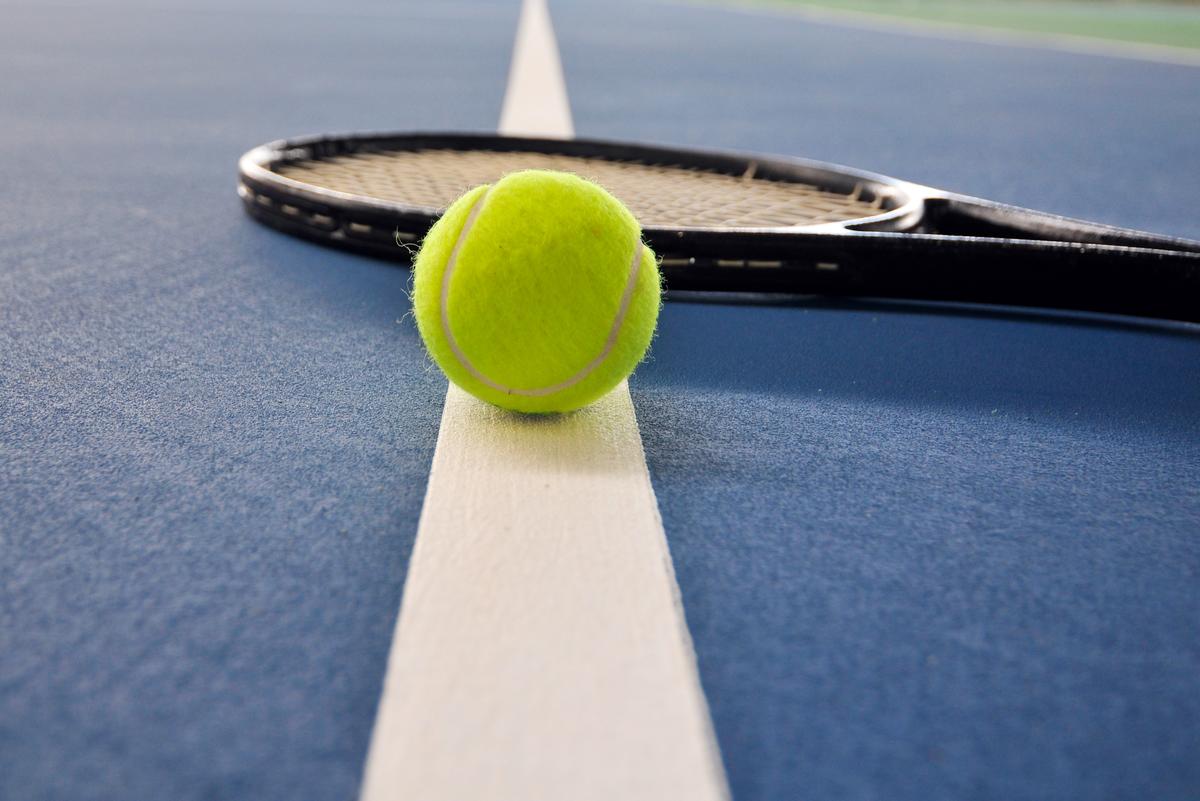 Tennis ball and racket on the BLUE court iStock-146913330.jpg