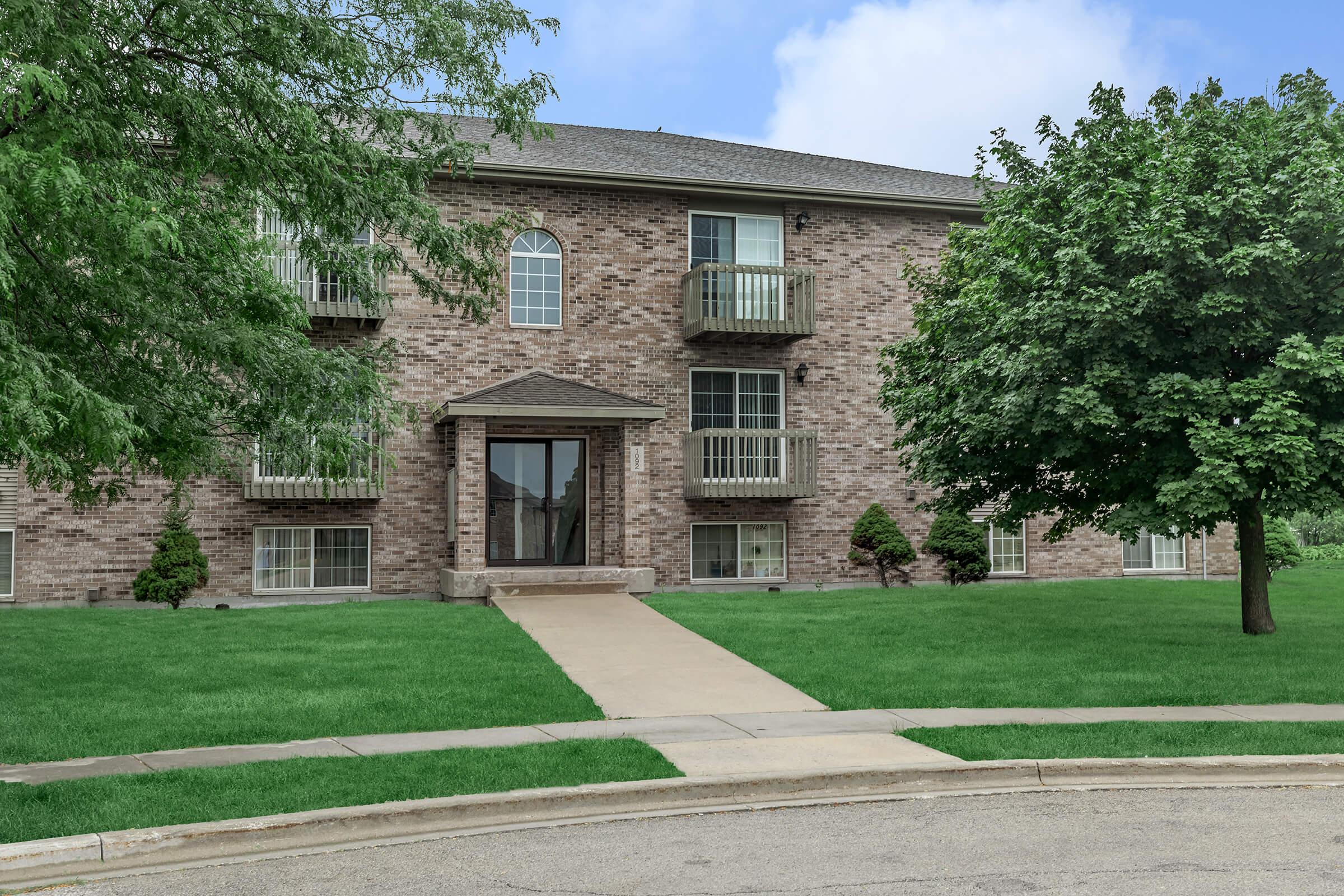 a large brick building with grass in front of a house