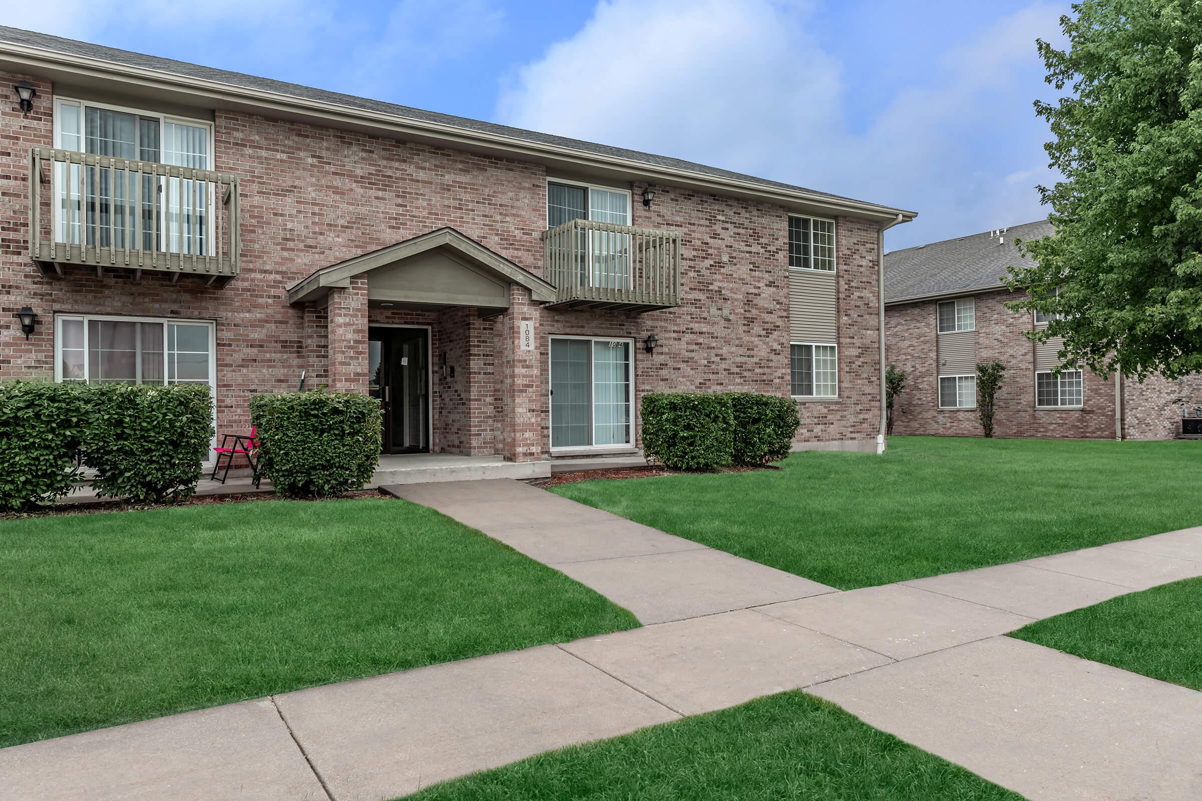 a large brick building with grass in front of a house