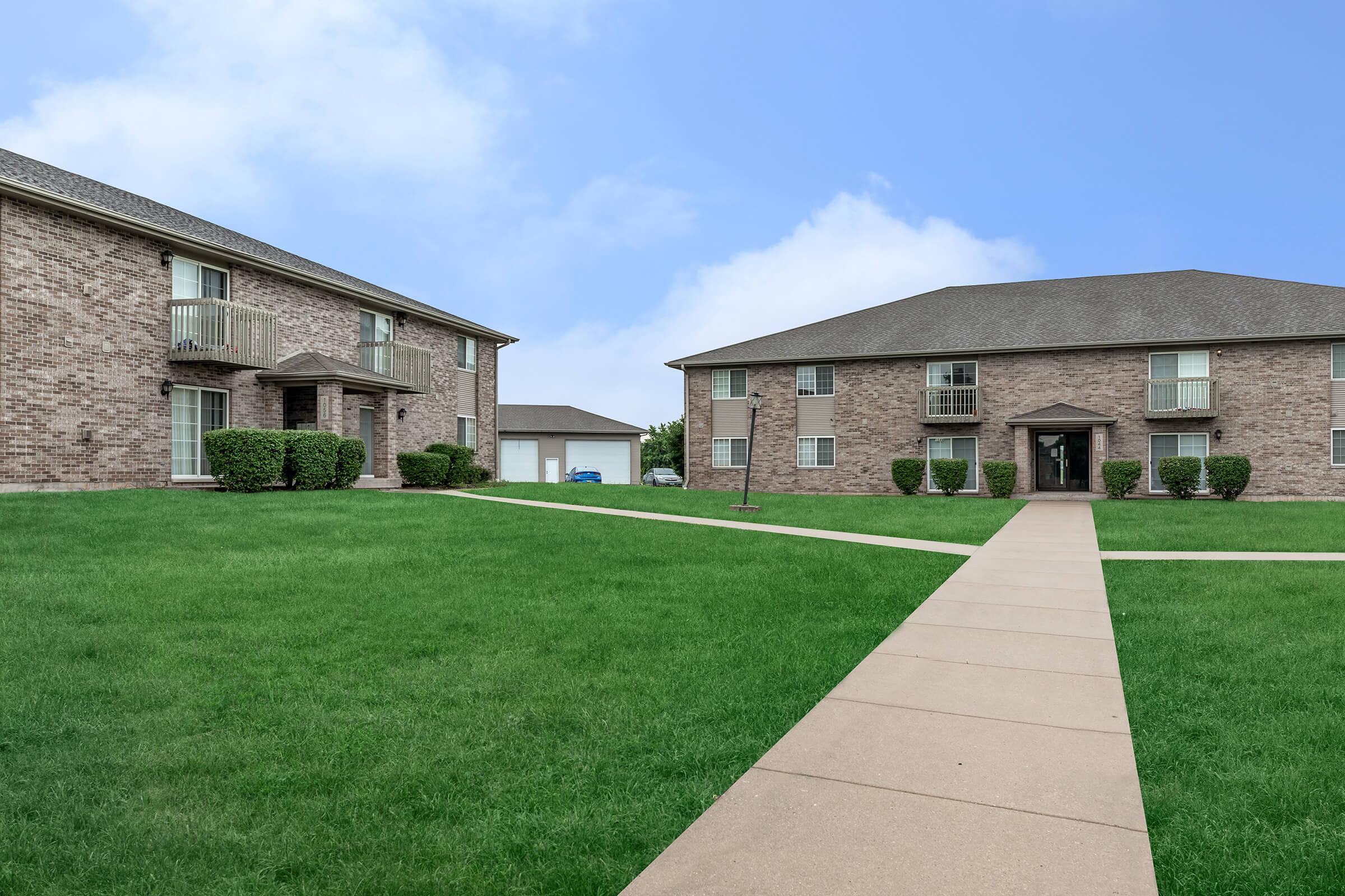 a large brick building with green grass in front of a house