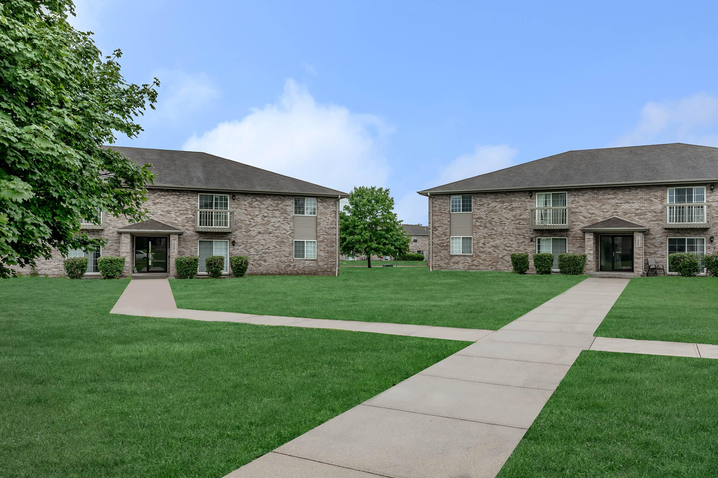 a house with a lawn in front of a brick building