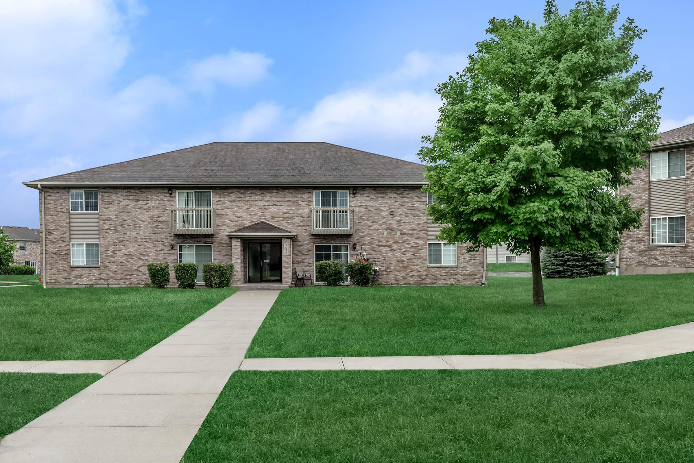 a house with a lawn in front of a brick building