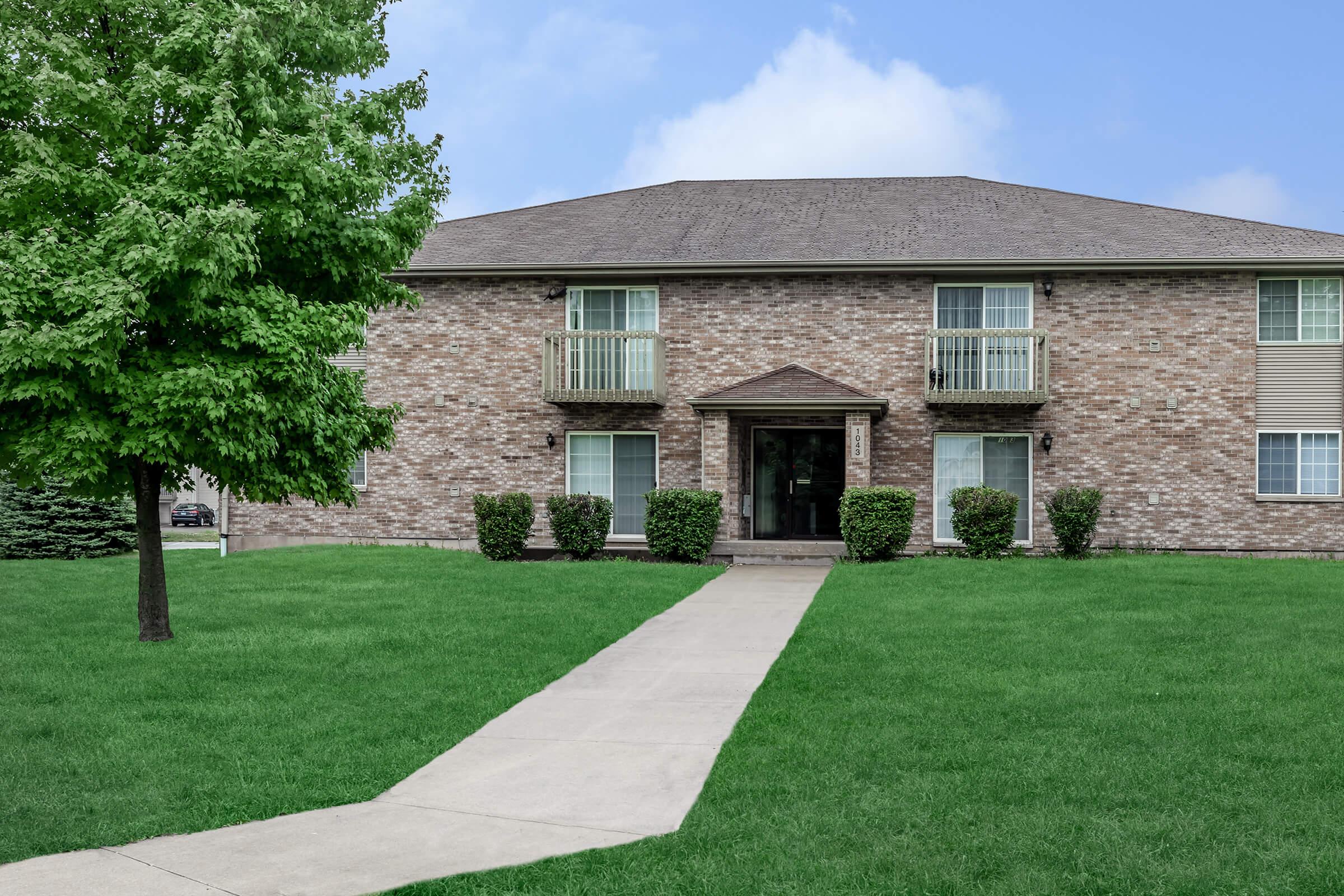 a house with a lawn in front of a brick building