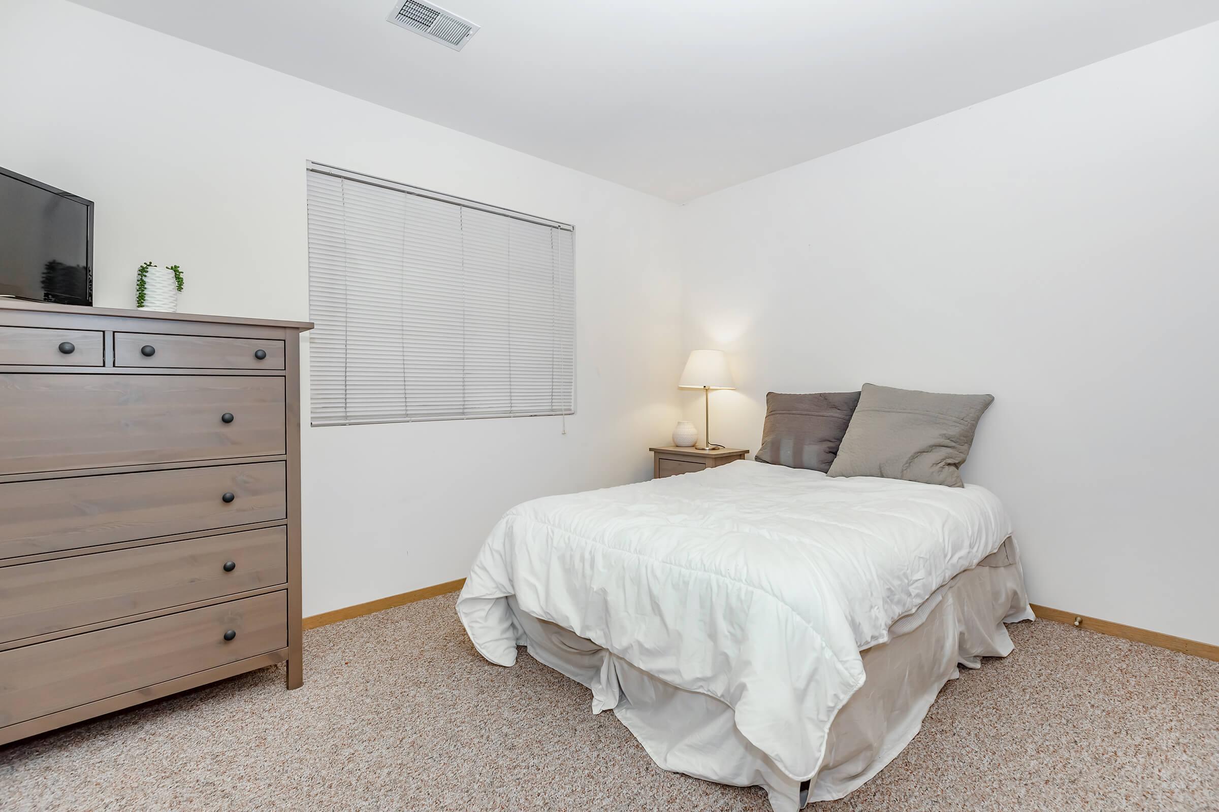 a bedroom with a bed and desk in a room