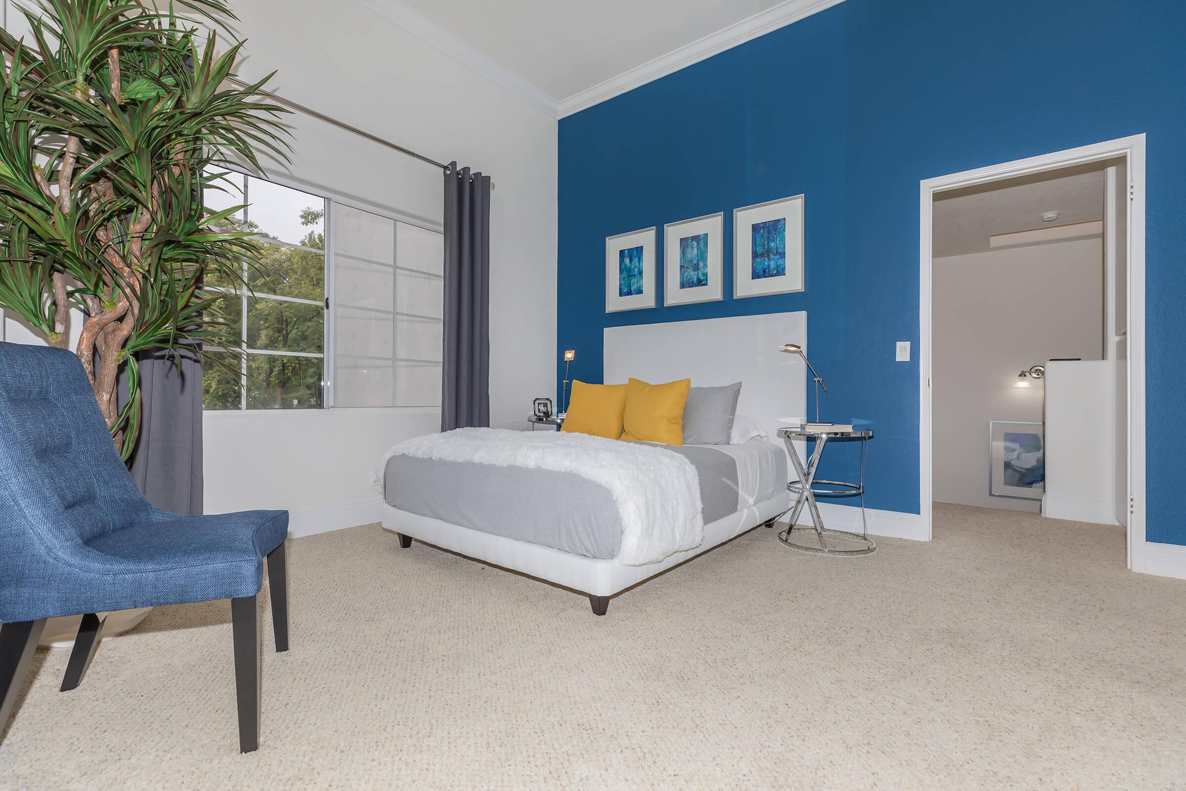 a bedroom with a bed and a chair in a room