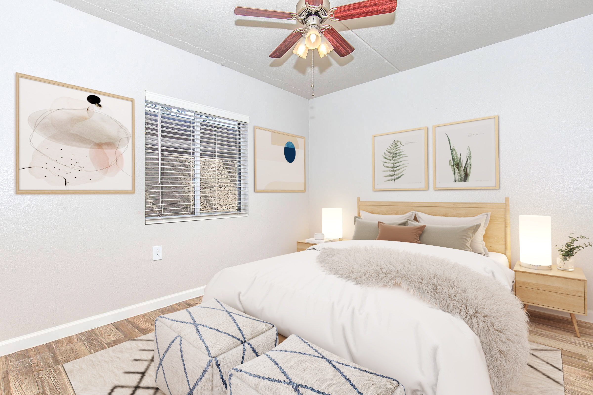 A cozy bedroom featuring a queen-sized bed with a soft blanket, decorative pillows, and a wooden headboard. Flanking the bed are two stylish lamps and a pair of knitted ottomans. The walls are adorned with framed artwork, and natural light streams through a window with blinds. A ceiling fan adds a modern touch.