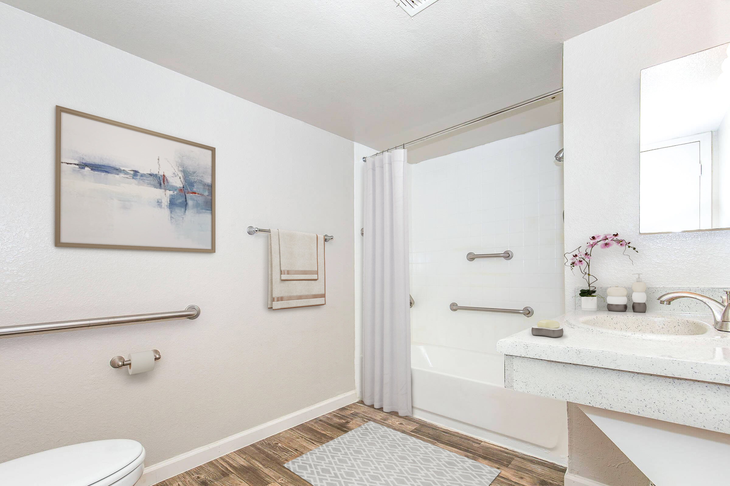 A clean and modern bathroom featuring a white bathtub with a shower curtain, a sink with a white countertop, hand towels hanging on the wall, and a framed abstract painting. The floor is covered with wood effect tiles, and there are decorative elements like candles and a plant on the sink.