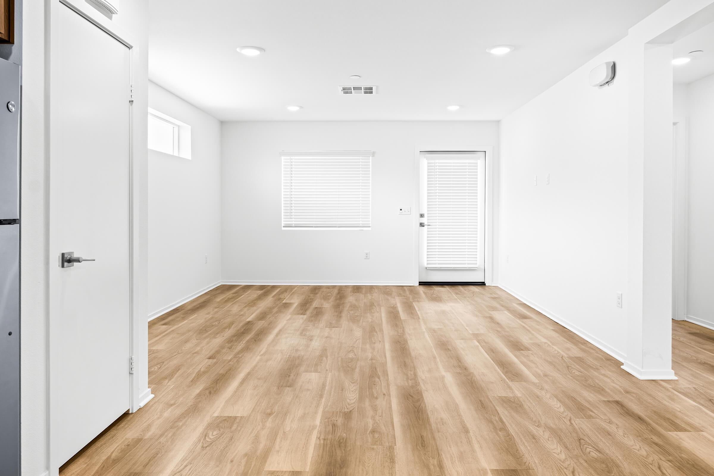 An empty room with light-colored walls and hardwood flooring. 