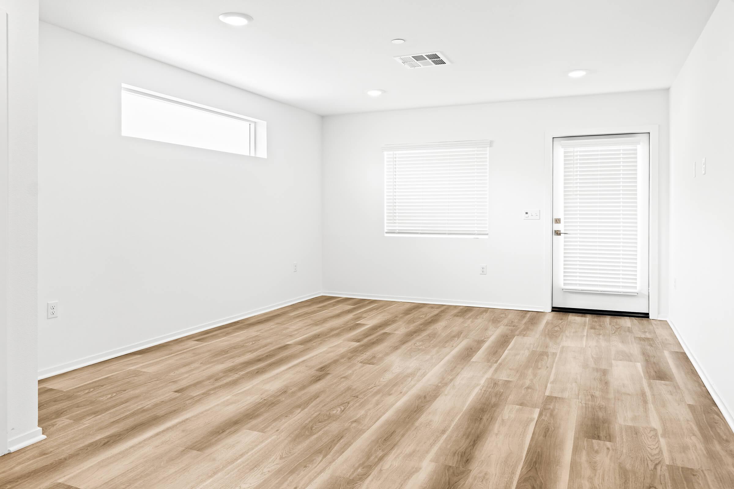 An empty room with light-colored walls and hardwood flooring. 