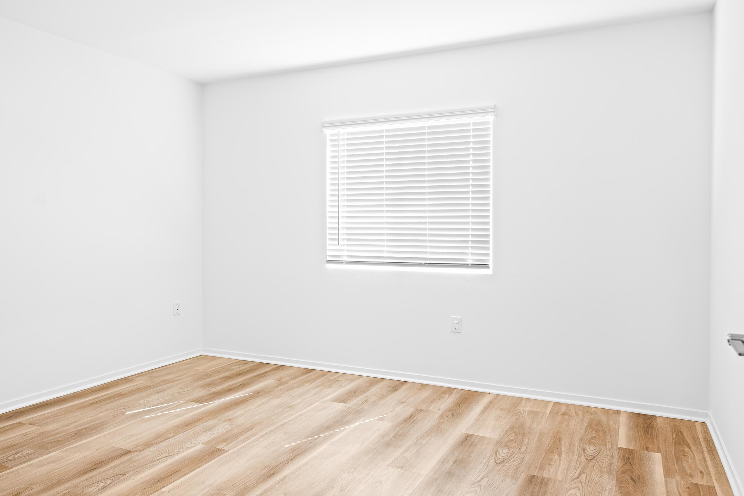 An empty room with light-colored walls and hardwood flooring. 