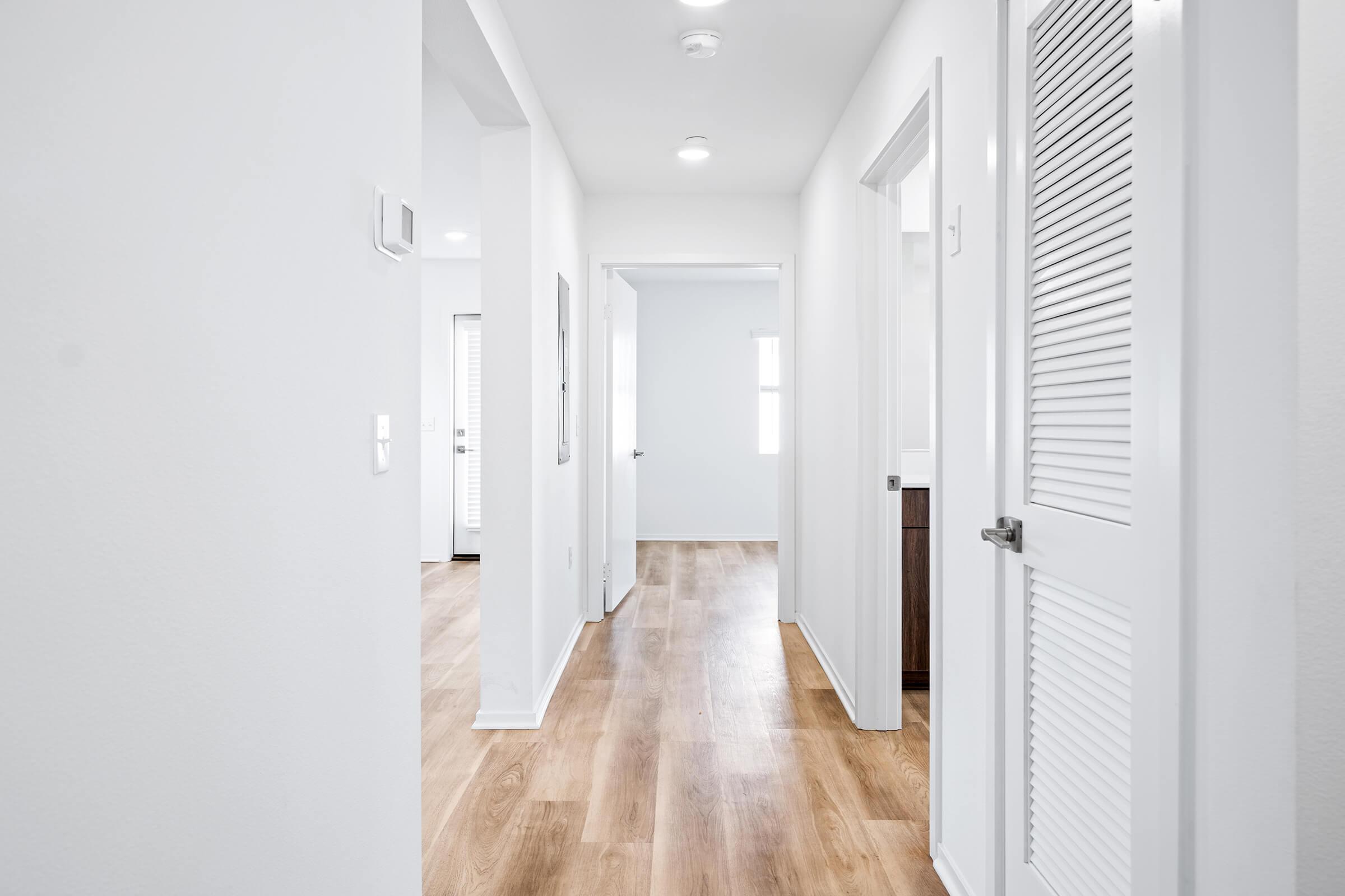 An empty hallway with light-colored walls and hardwood flooring. 