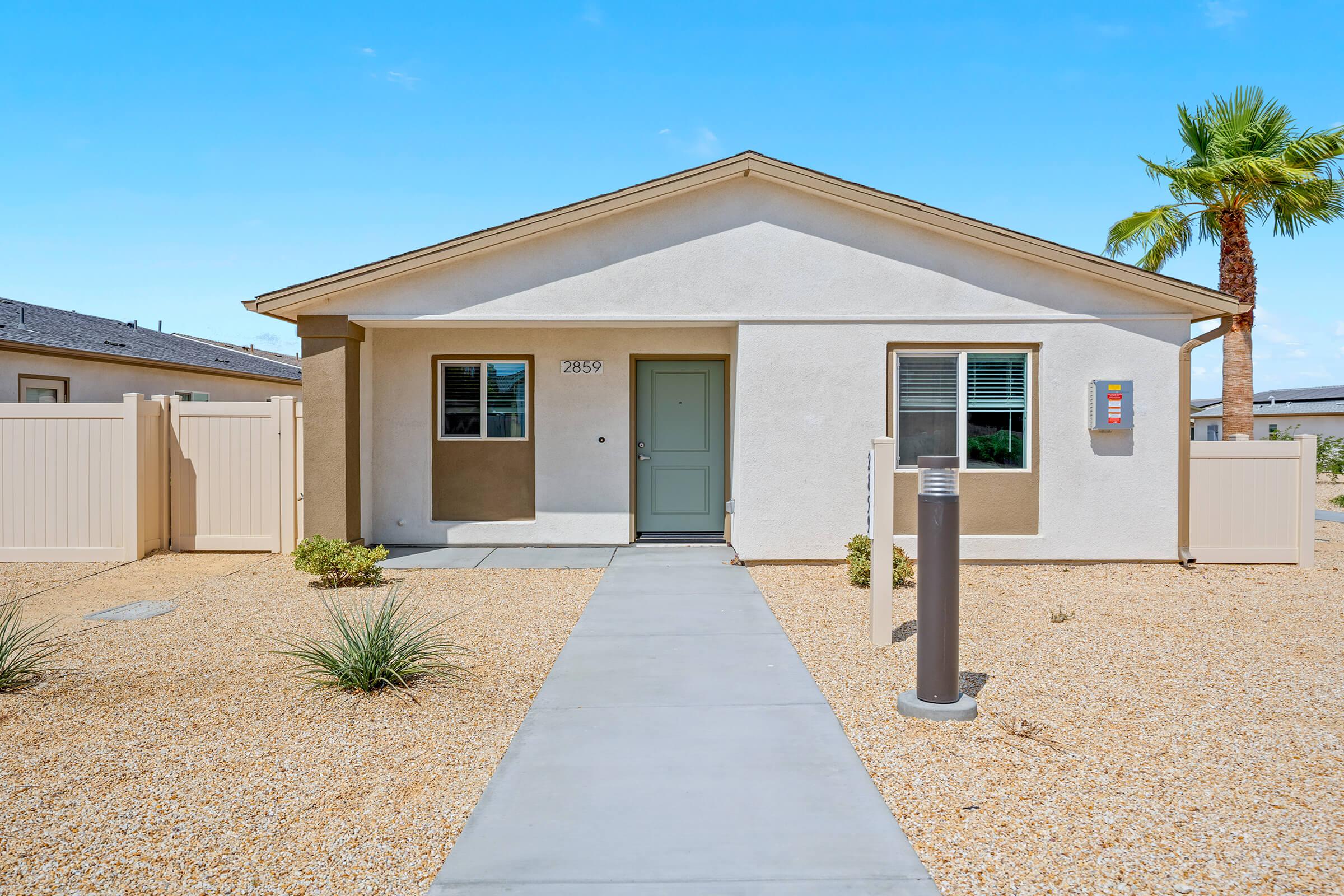 A single-story house with a front yard that features gravel landscaping, a pathway leading to the entrance, and a few small plants.