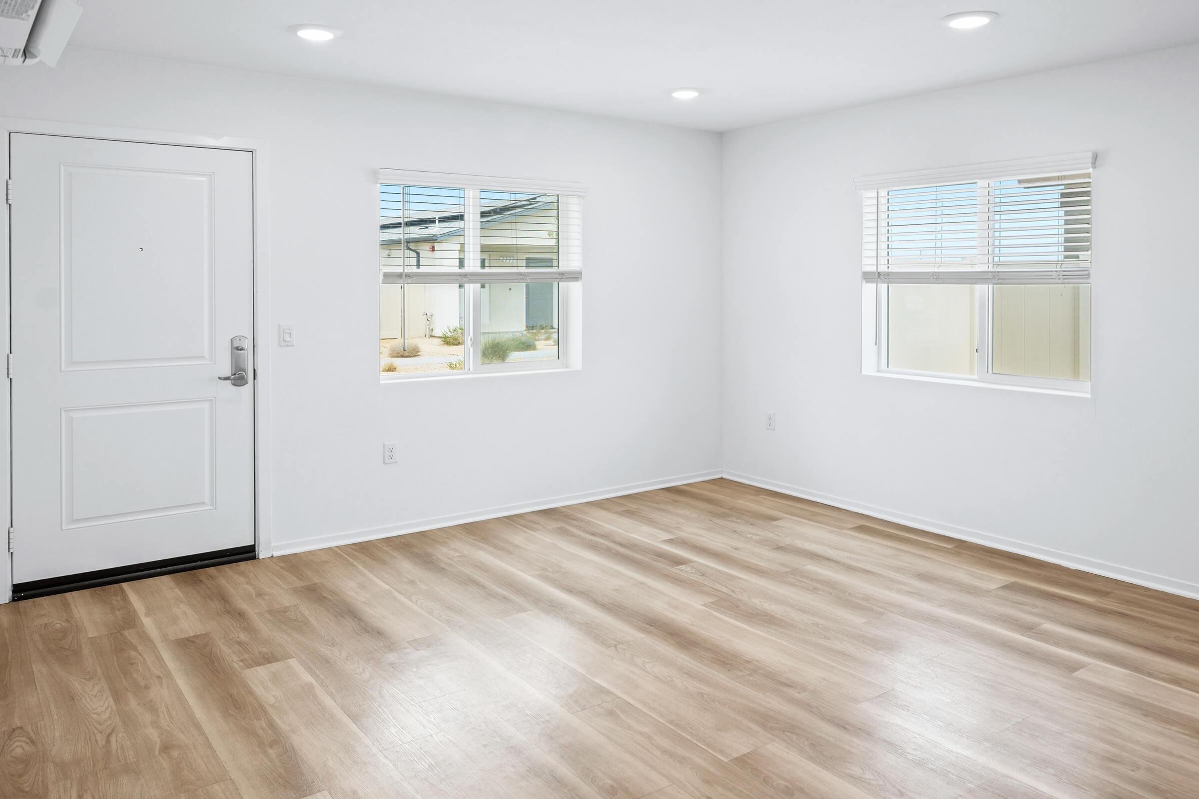 An empty room with light-colored walls and hardwood flooring. 