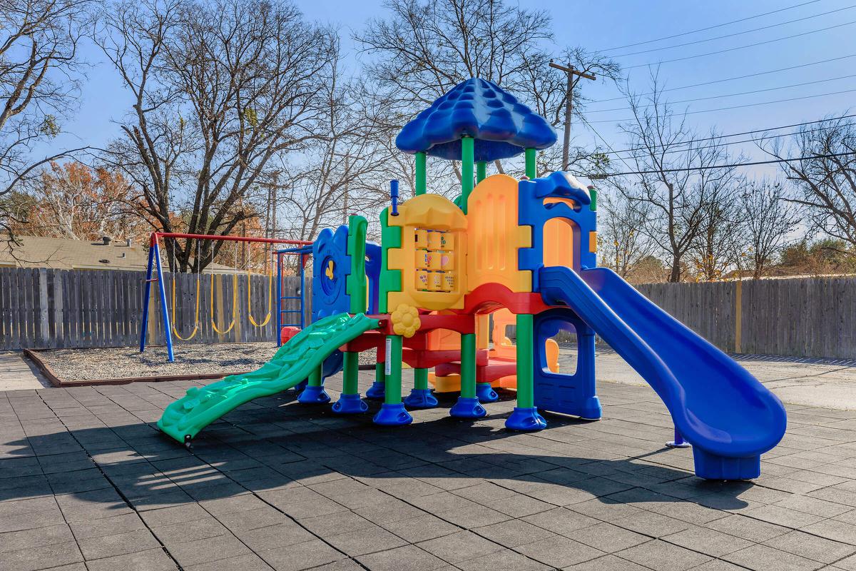 a playground with a blue umbrella