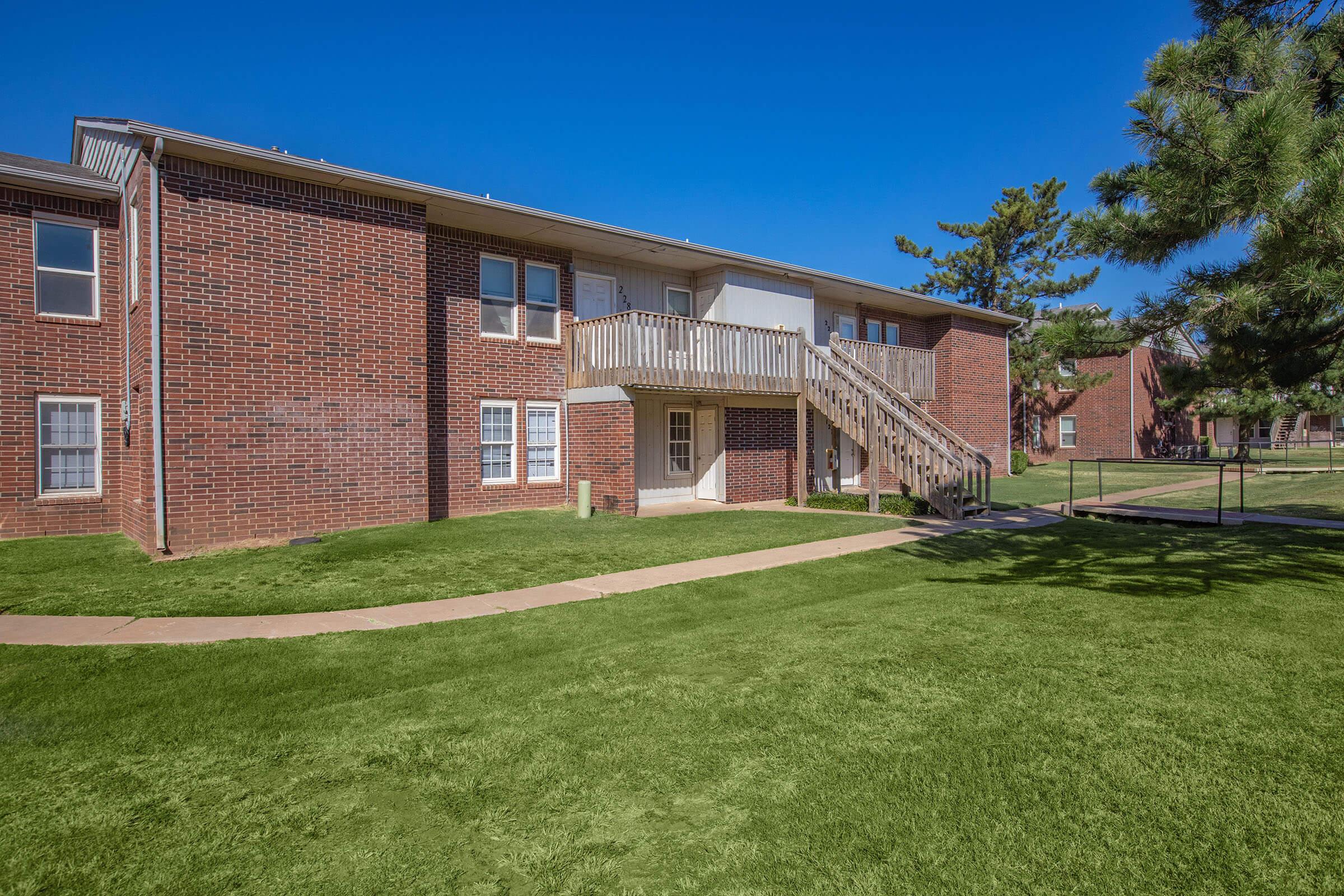 a large brick building with grass in front of a house