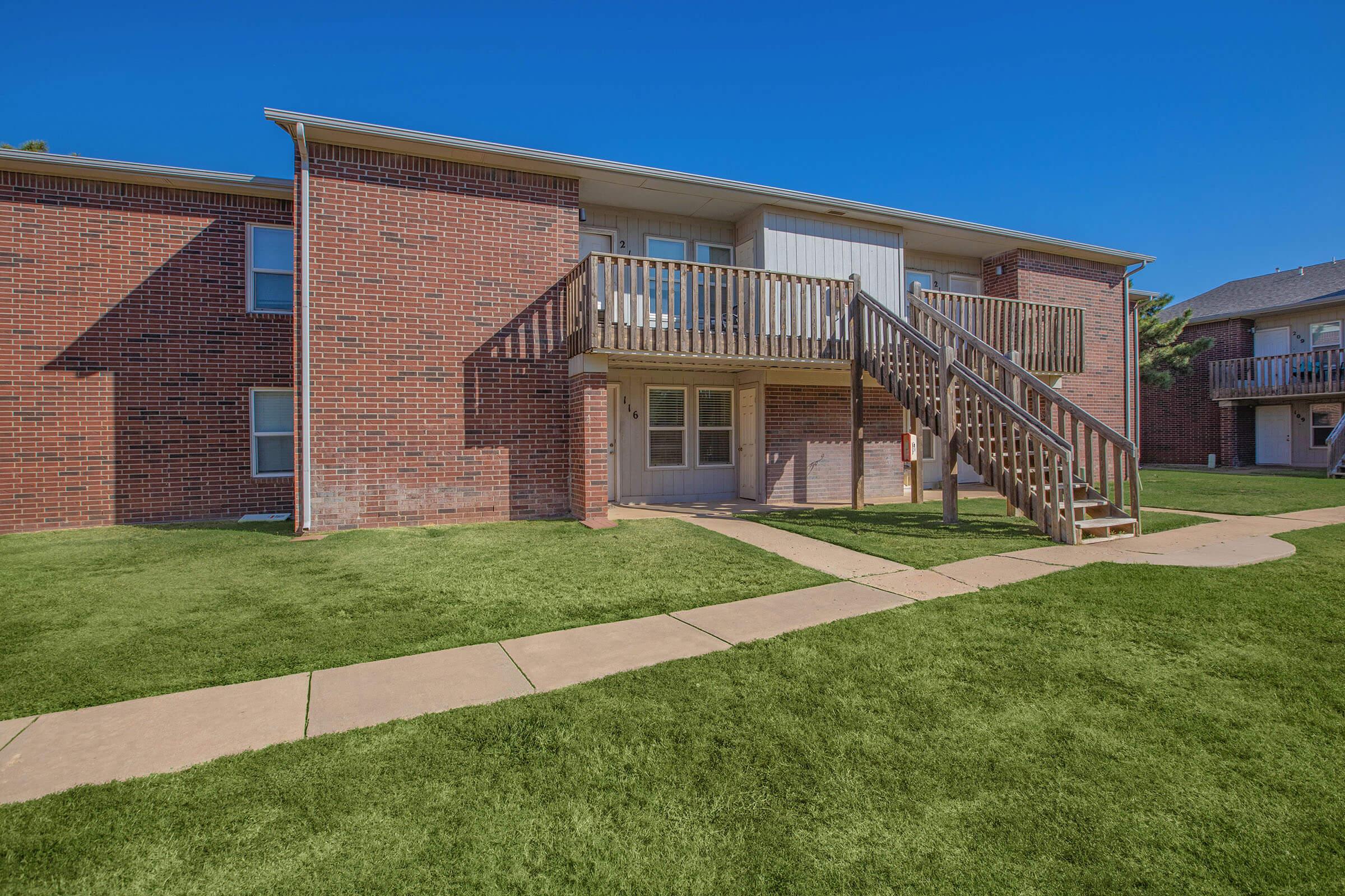 a large brick building with grass in front of a house