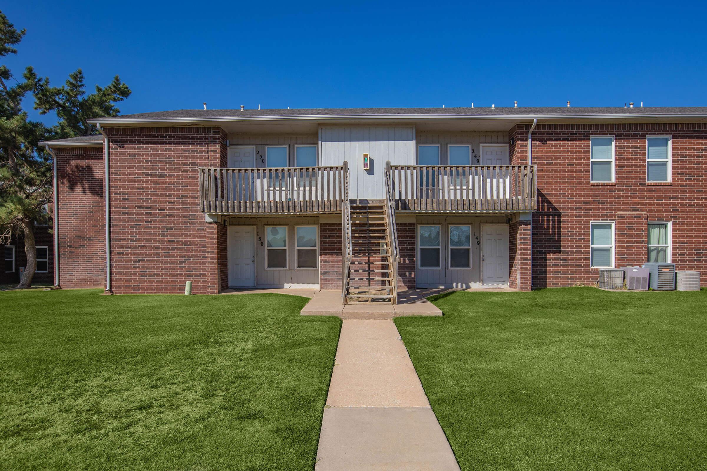 a large brick building with grass in front of a house