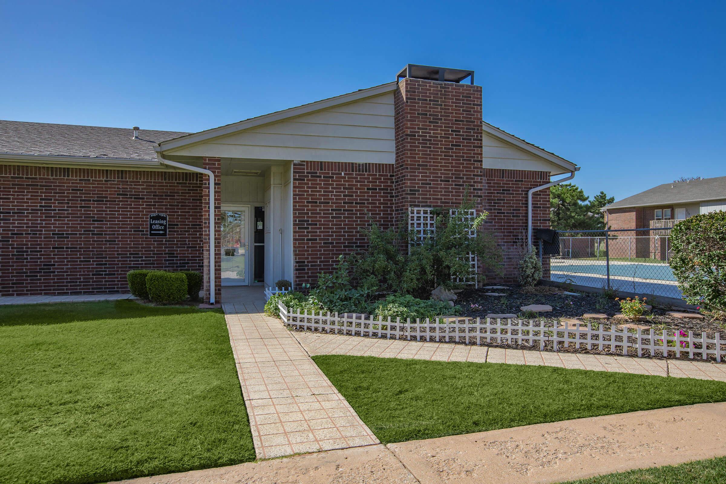 a house with a lawn in front of a brick building