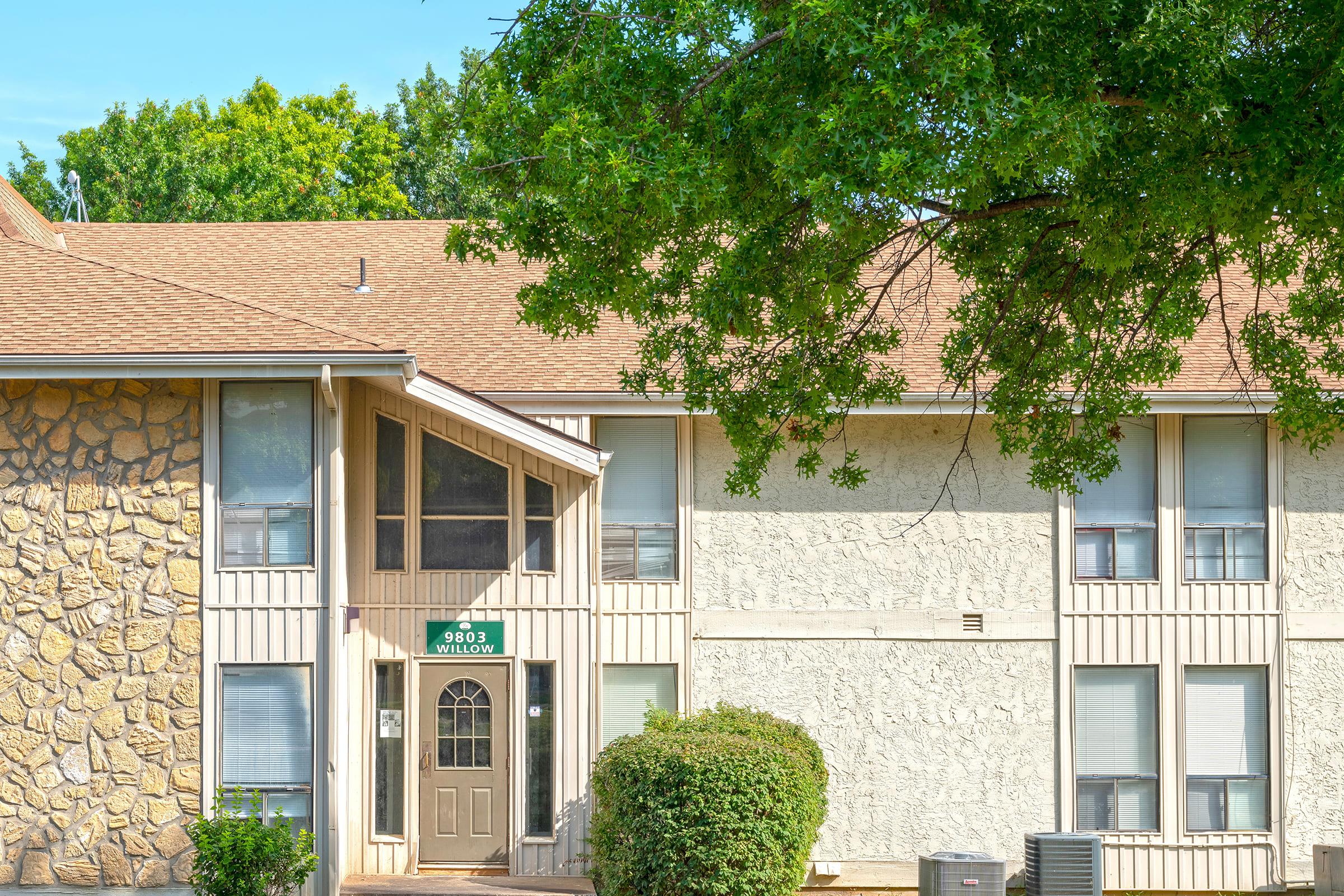 a house with bushes in front of a brick building