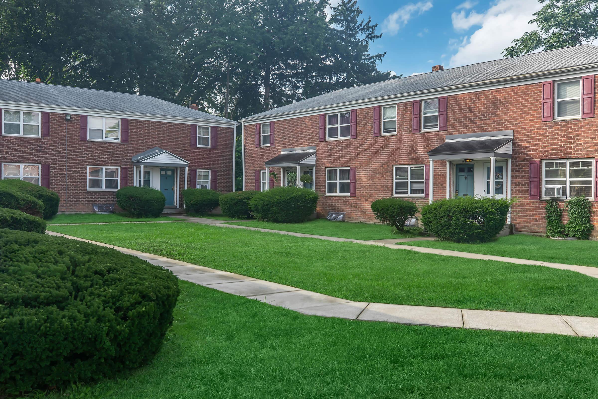 a large brick building with grass in front of a house