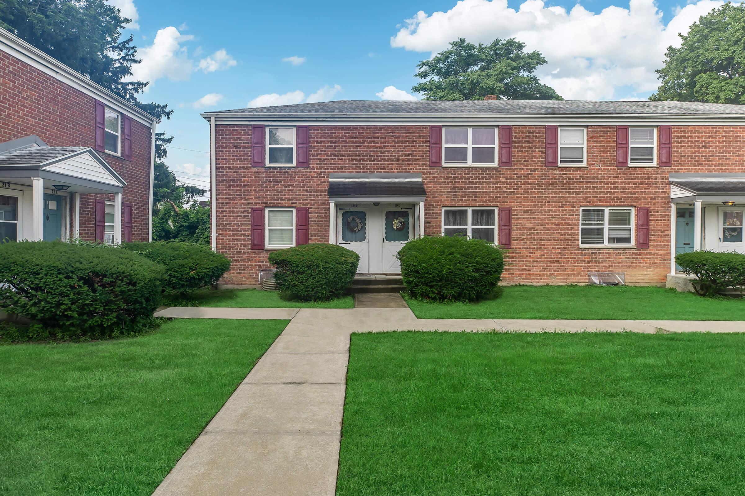 a large brick building with grass in front of a house