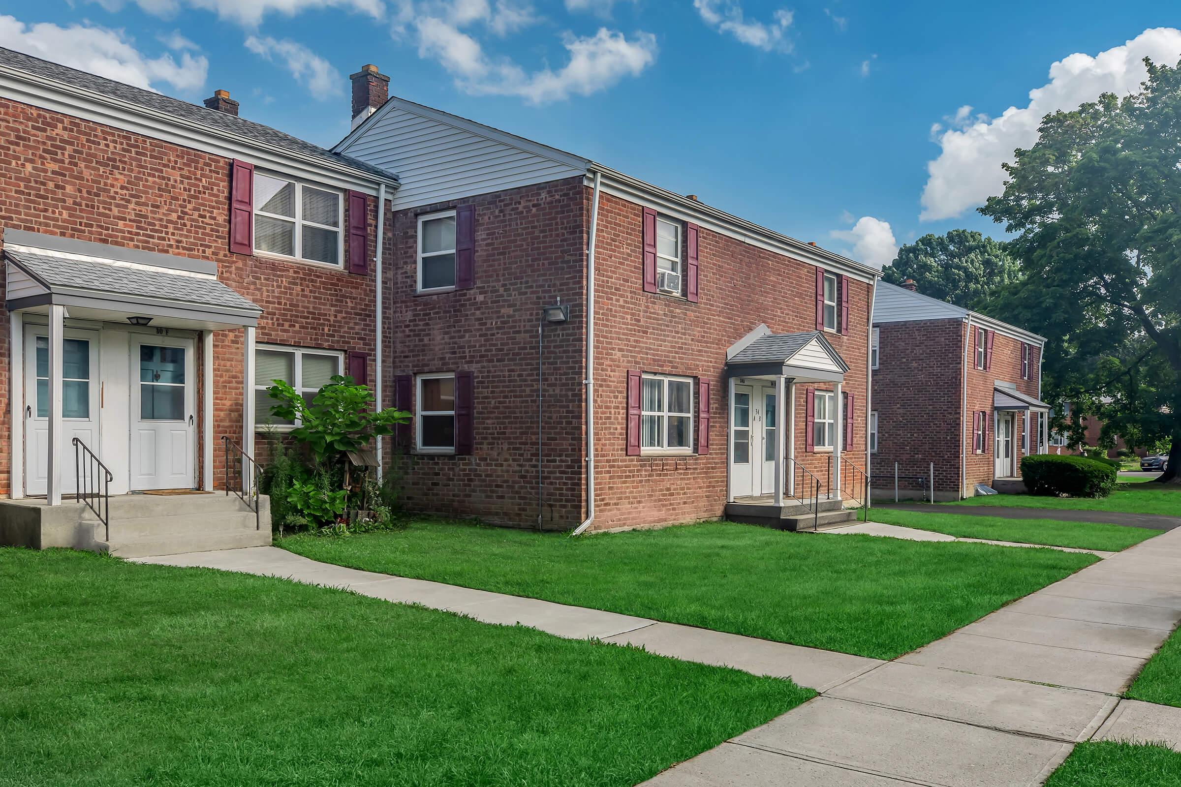 a large brick building with grass in front of a house