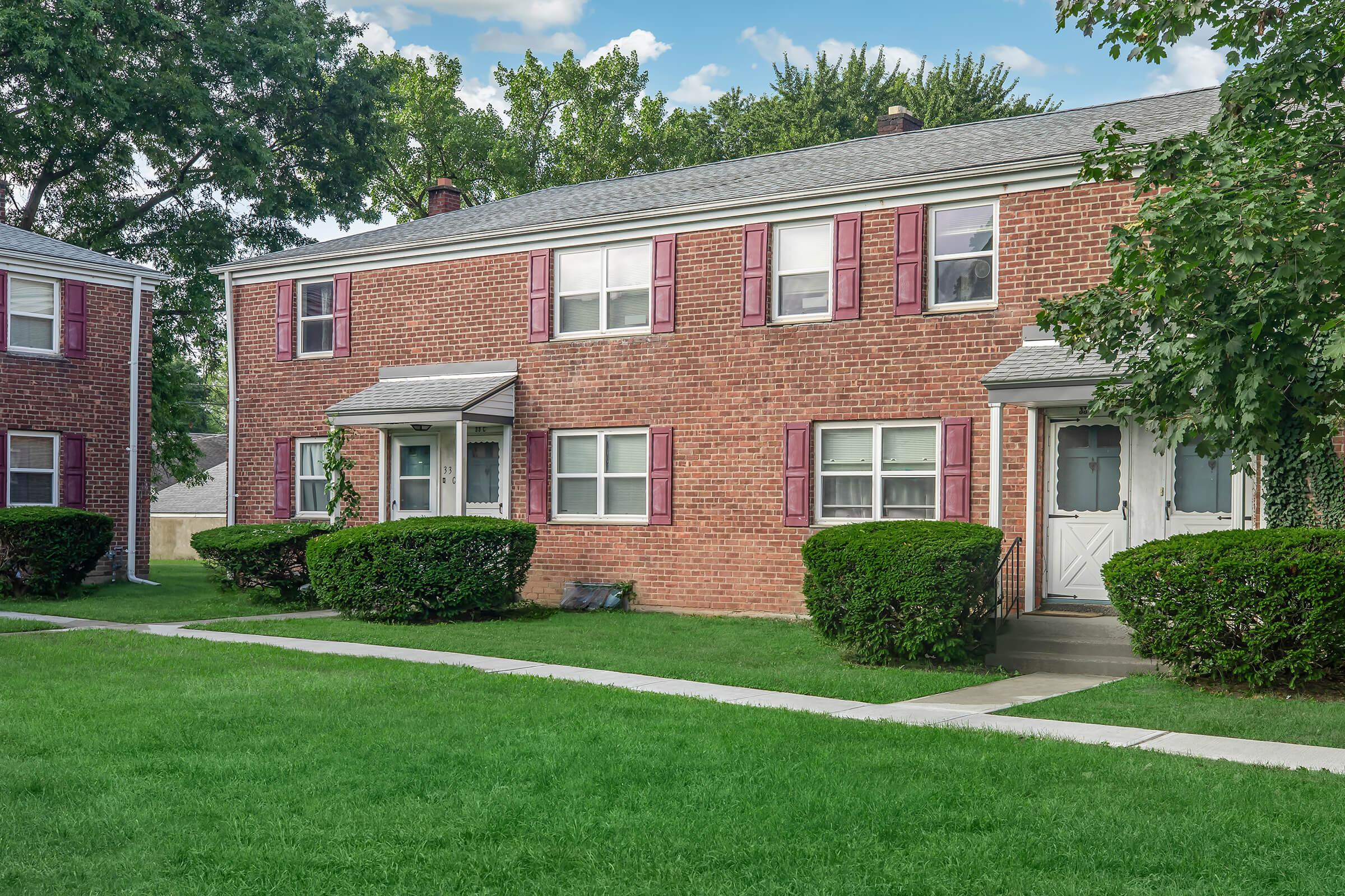 a house with a lawn in front of a brick building