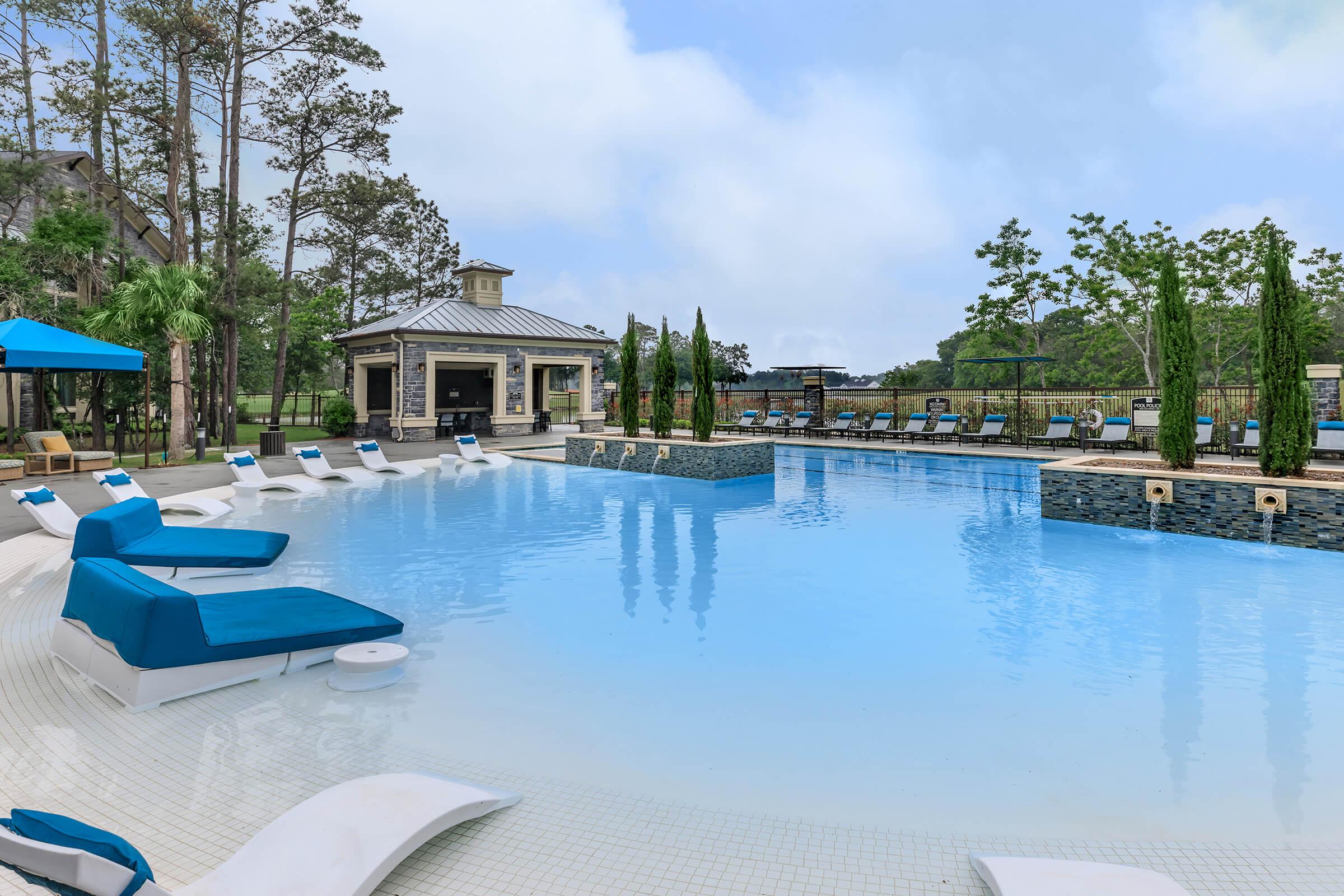 Beach entry section of the resort style pool at Park at Tour 18. Water lounge chairs spaced around.