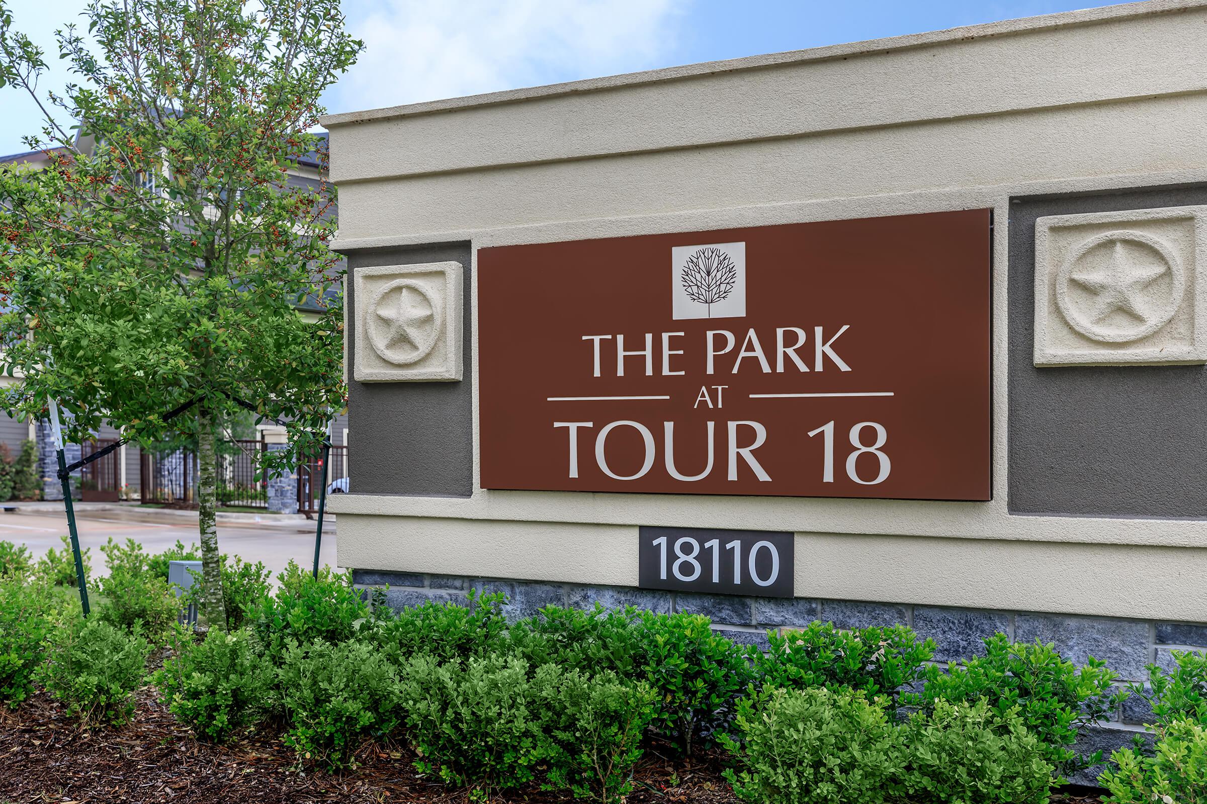 Park at Tour 18 monument sign in red with landscaping surrounding.