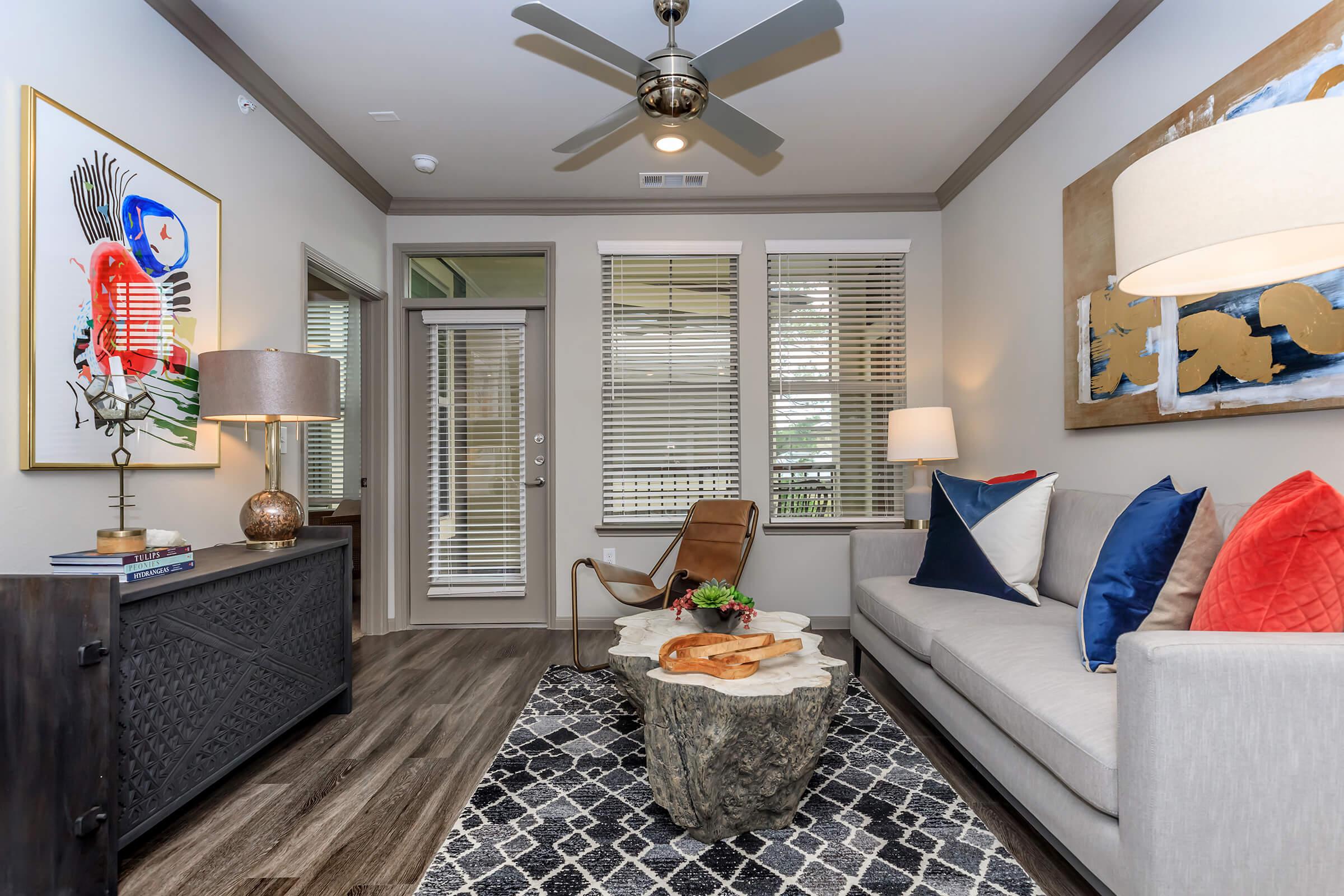Furnished living room with ceiling fan and wood flooring.