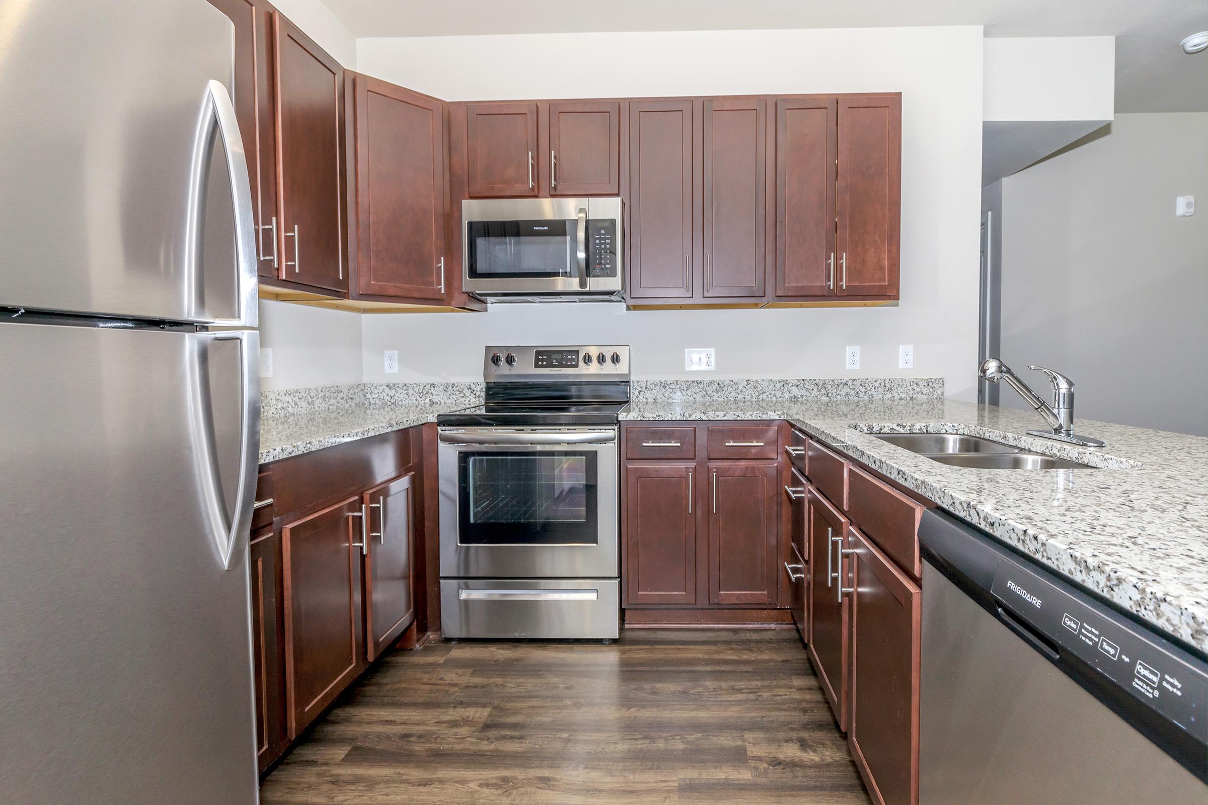 a large kitchen with stainless steel appliances and wooden cabinets