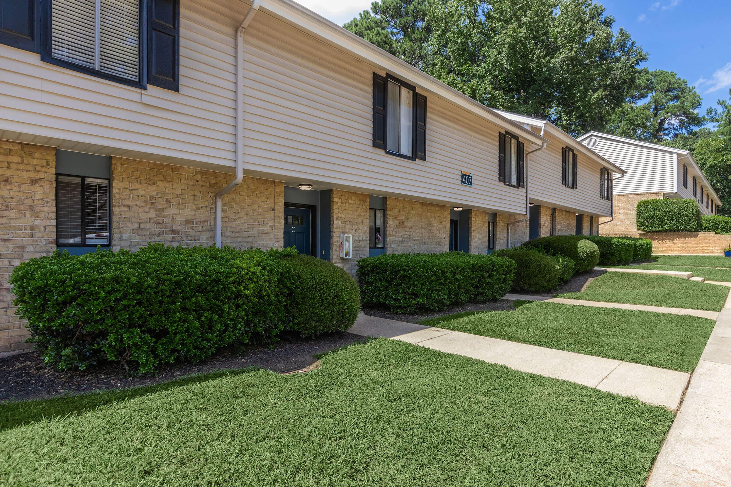 a house with a lawn in front of a brick building