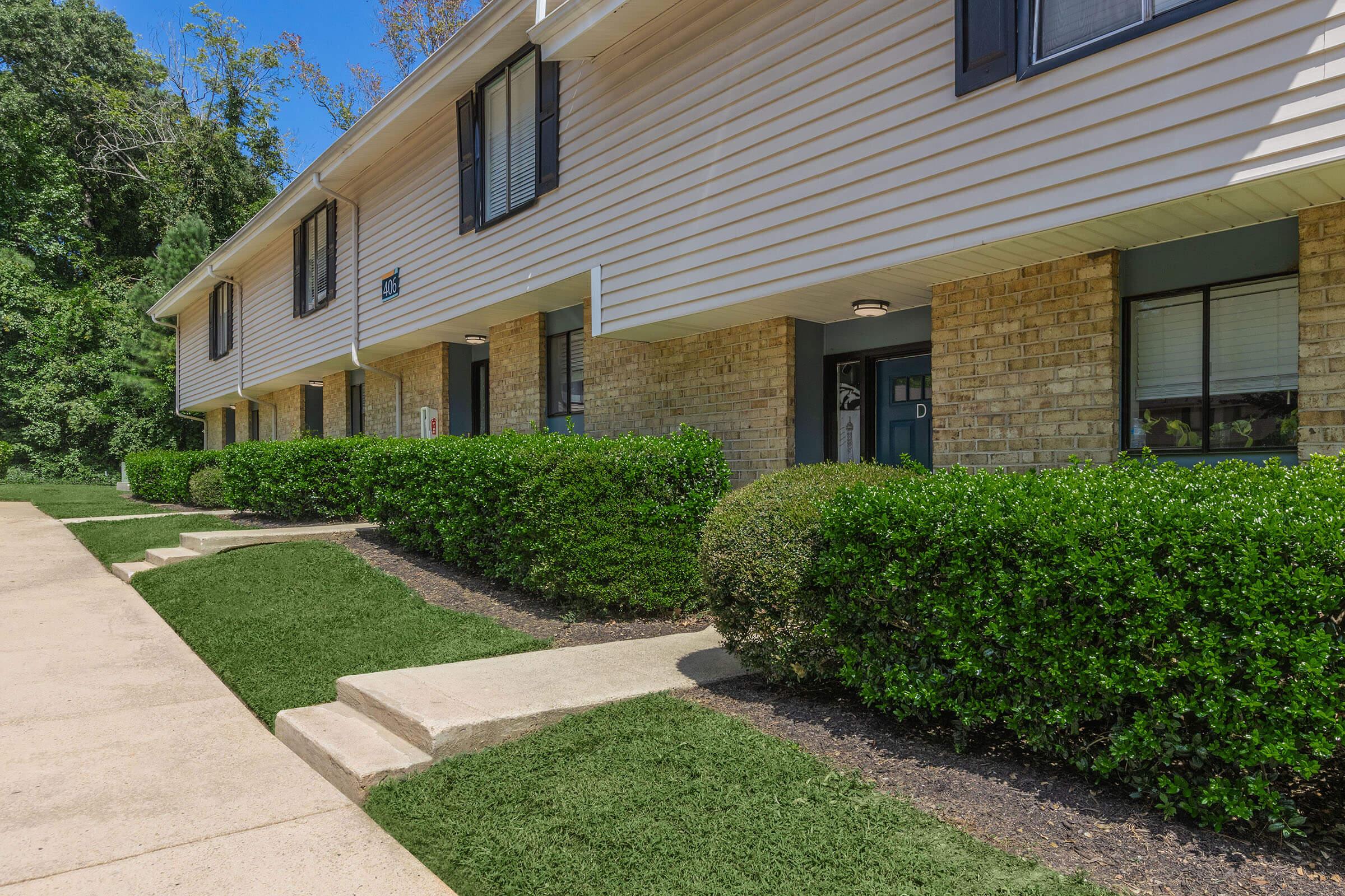 a large brick building with grass in front of a house