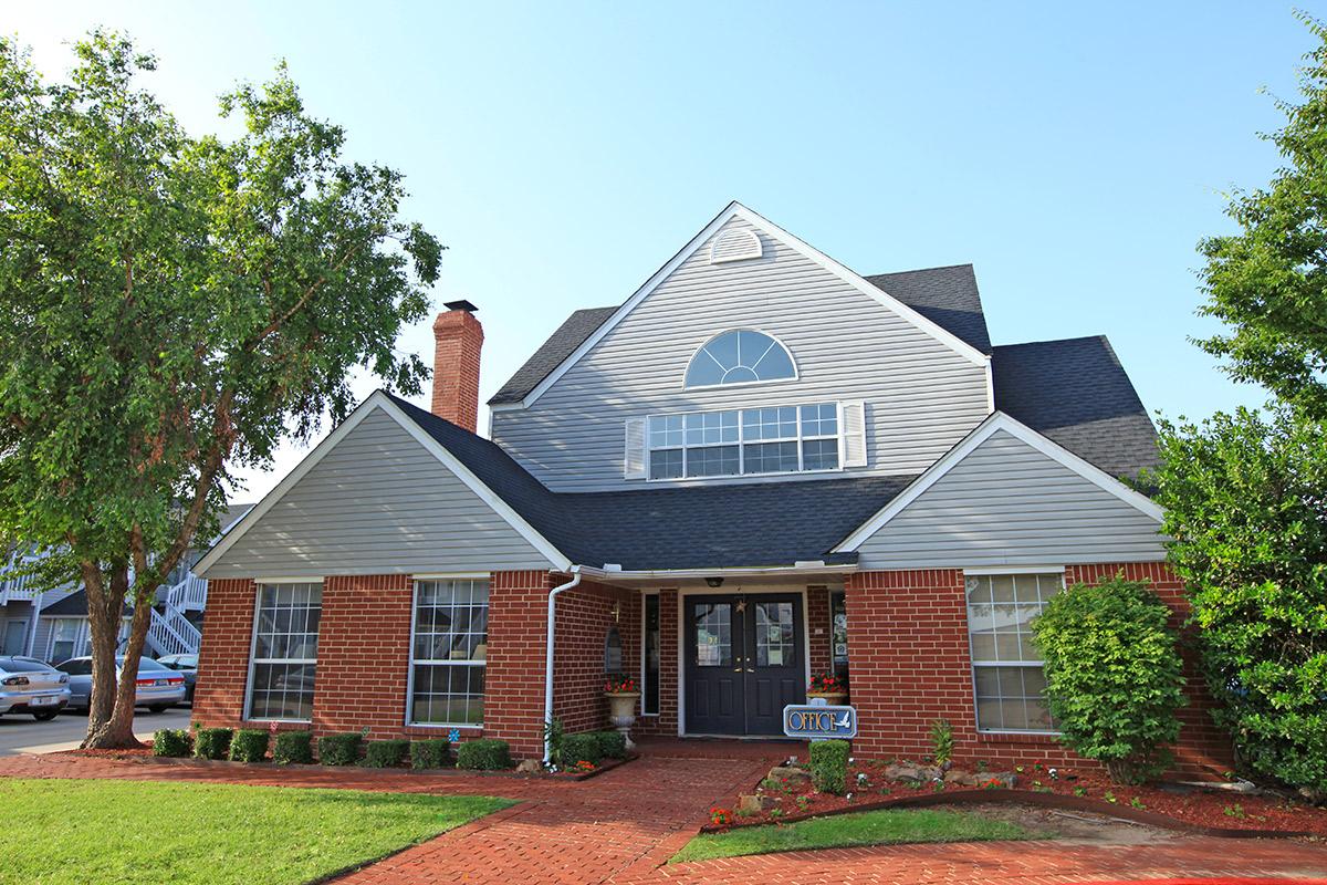 a large brick building with grass in front of a house