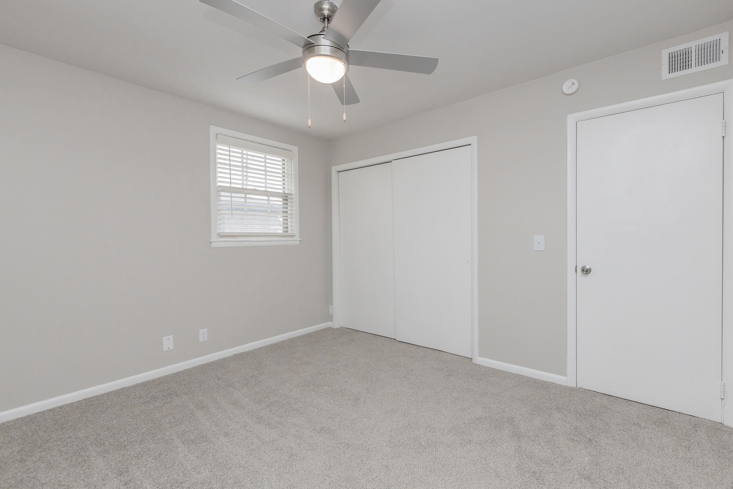 Carpeted bedroom with ceiling fan.