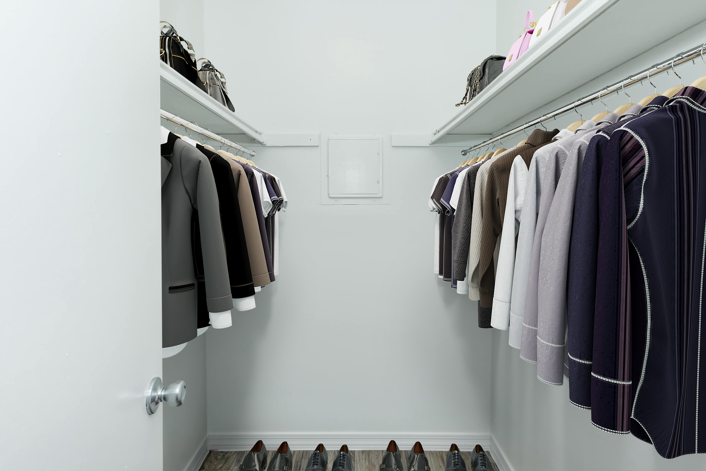 A spacious closet featuring organized clothing on hangers, predominantly blazers in various colors, and a row of neatly arranged shoes on the floor. The closet has white walls and shelves, with additional bags placed on top, creating a tidy and stylish storage space.