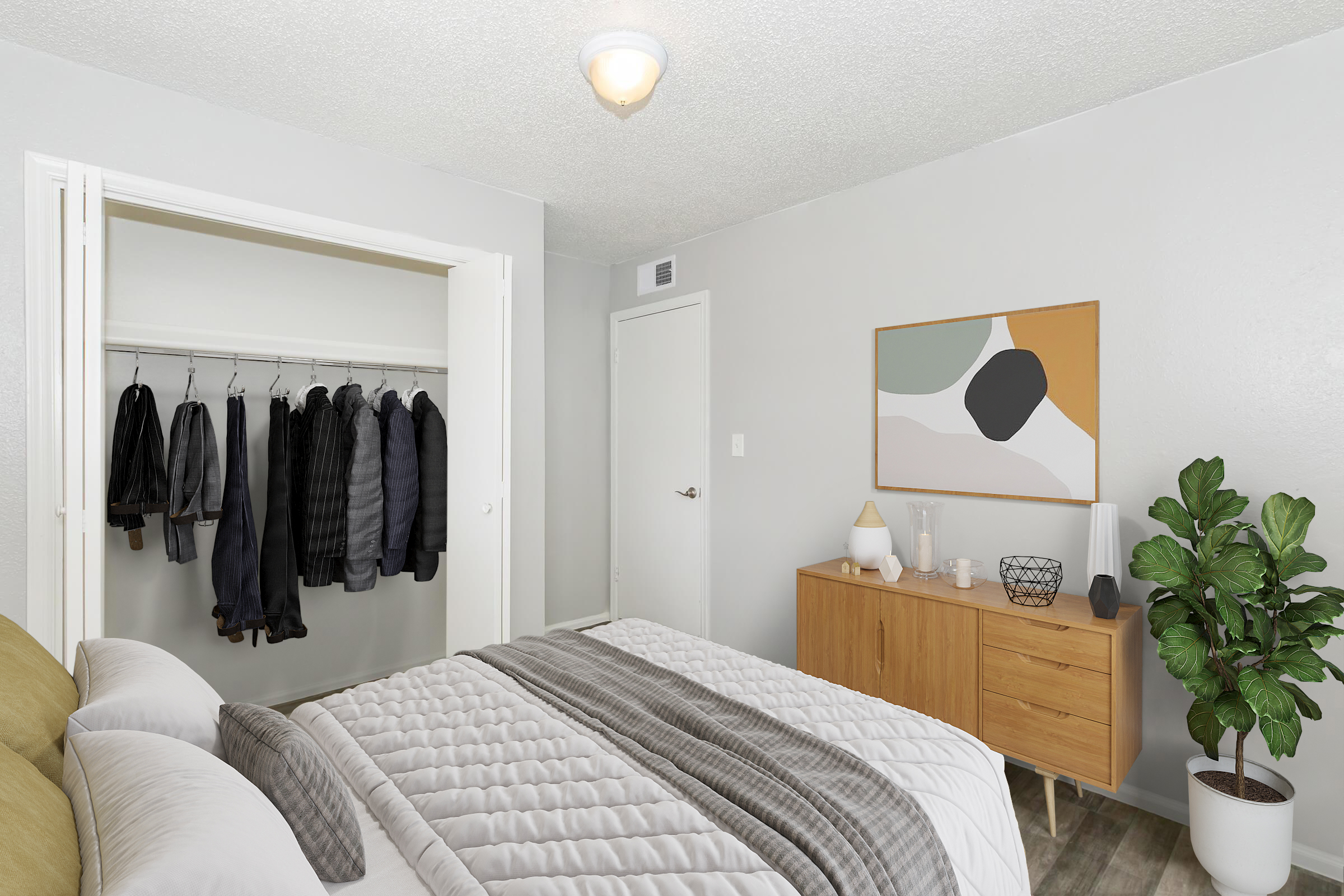 A well-decorated bedroom featuring a bed with gray and beige bedding, a wooden dresser with decorative items, and a potted plant. A closet with hanging clothes is visible in the background, along with a door leading to another area. A piece of abstract wall art adds a modern touch to the space.
