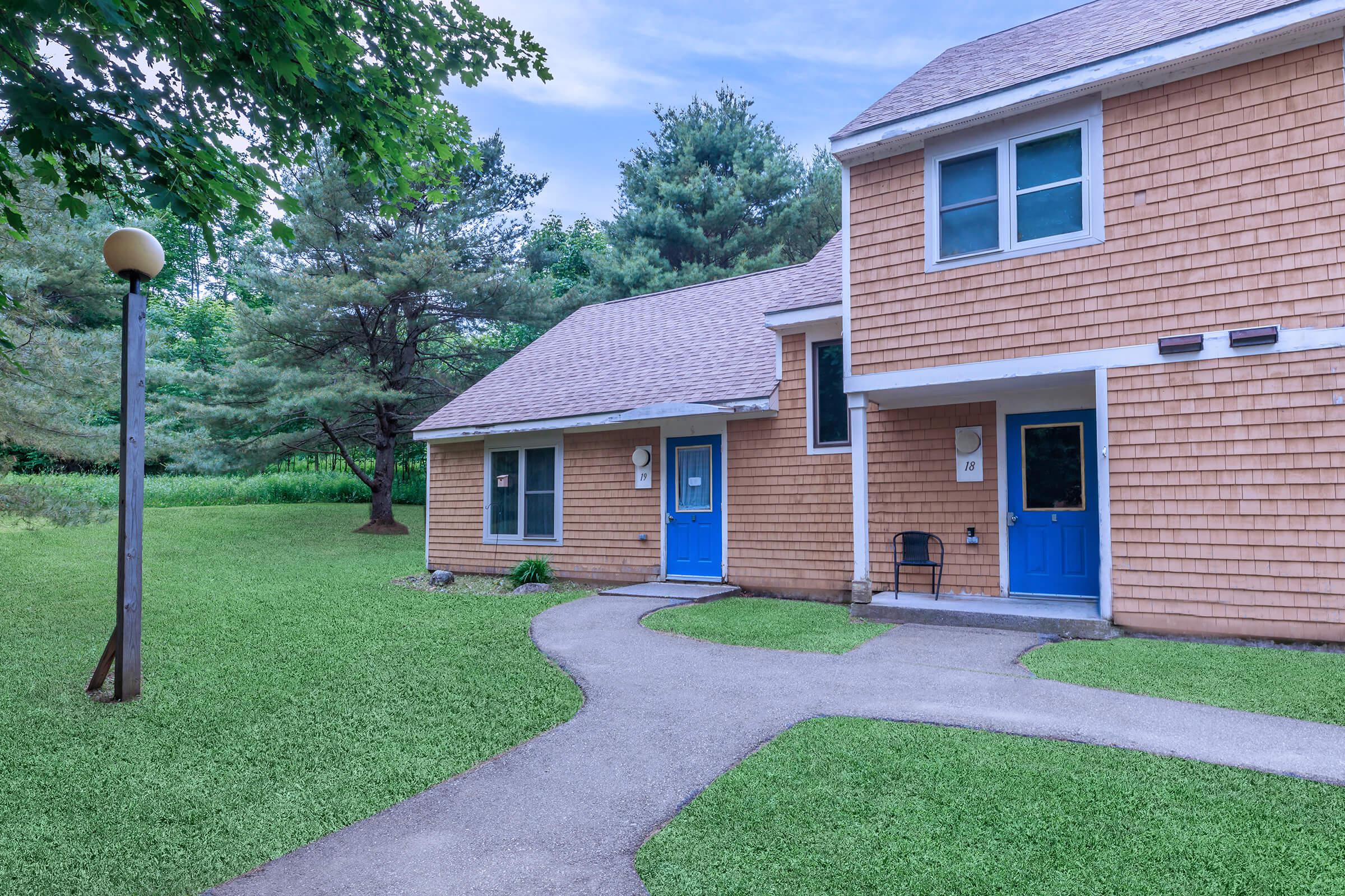 a house with a lawn in front of a brick building