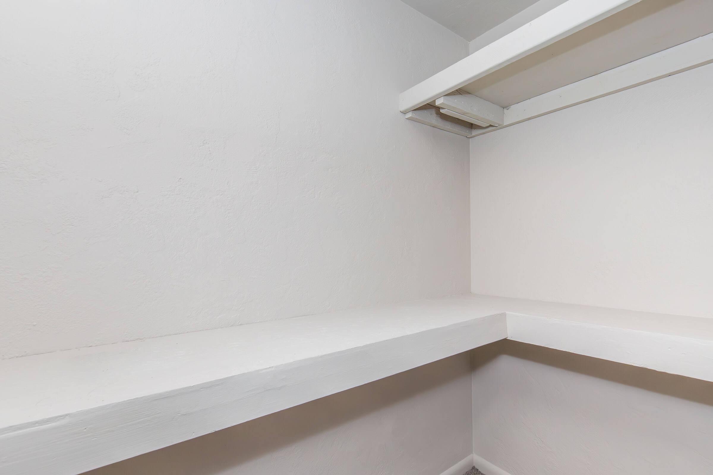 A clean, empty closet with white walls and a single shelf. The floor is visible, and the overall space appears bright and minimalistic, ideal for storage.