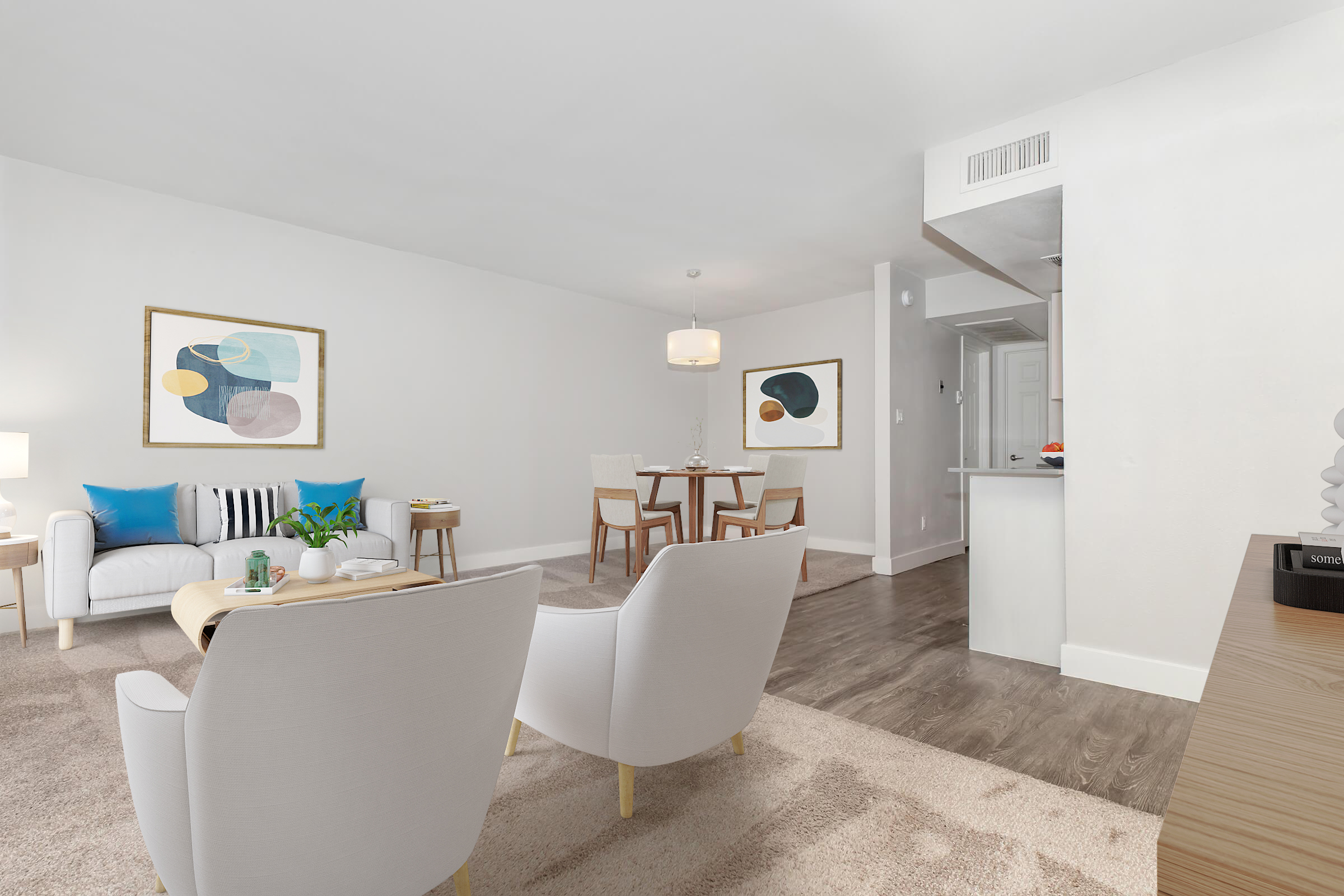 A modern living room featuring a white sofa with blue and striped cushions, two light-colored armchairs, a wooden dining table with chairs, and decorative artwork on the walls. There are neutral-toned carpets and a stylish lamp, creating a cozy and inviting atmosphere.
