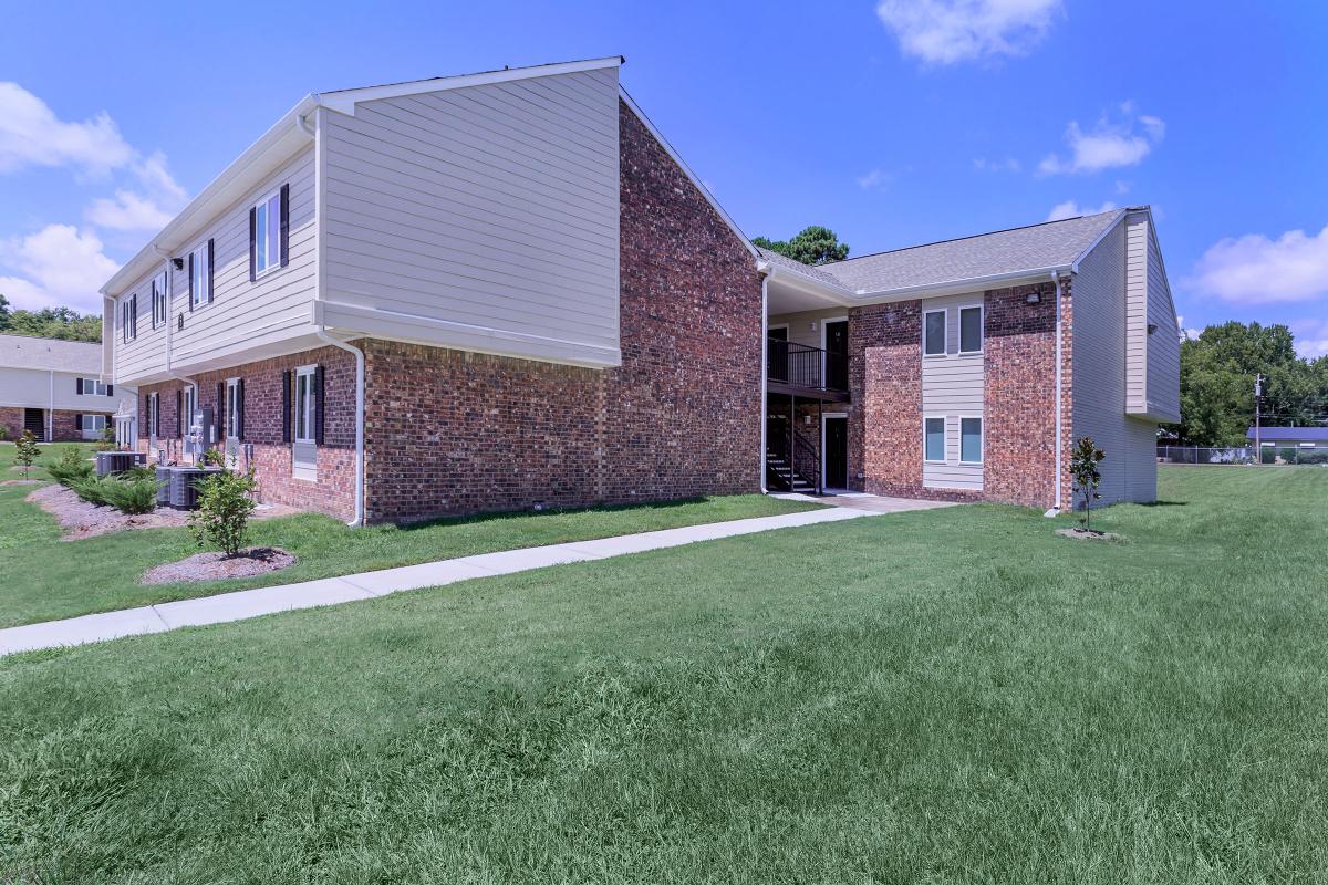 a house with a lawn in front of a brick building