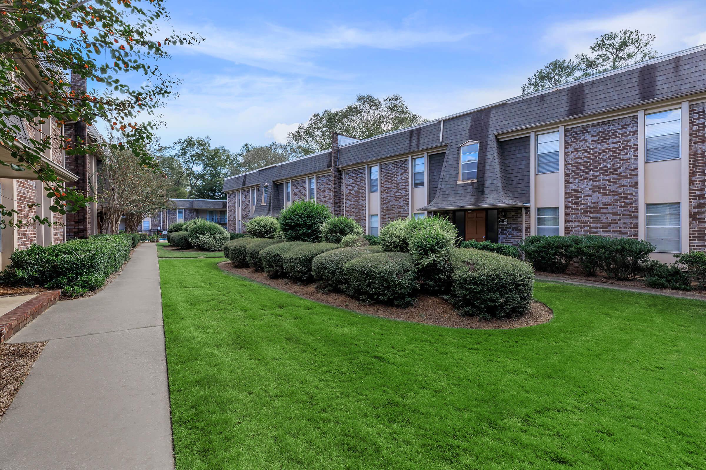a large brick building with green grass